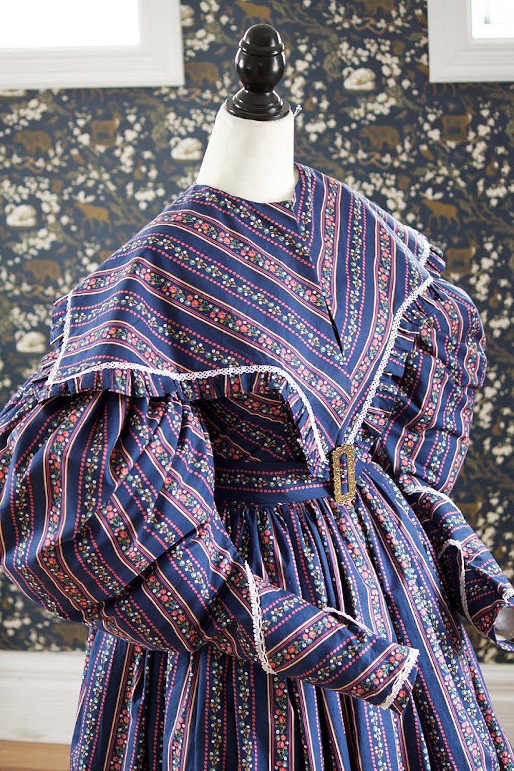 1830s cotton gown with puffed gigot sleeves. It is worn over a corded and flounced petticoat. Enquire for Bespoke Fitted pricing.