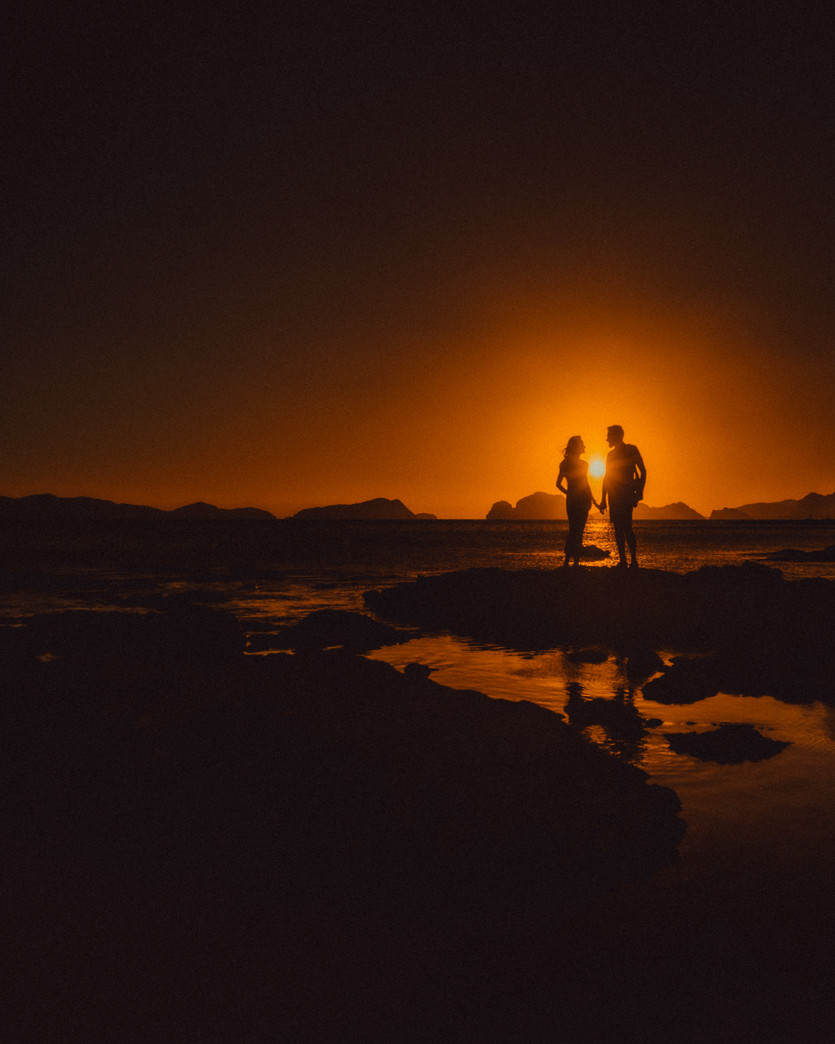 Golden hour moody travel couple silhouettes, just minutes before sunset, Las Cabanas Beach, El Nido, Palawan, Philippines, Southeast Asia, February 2019, Sony A7III.