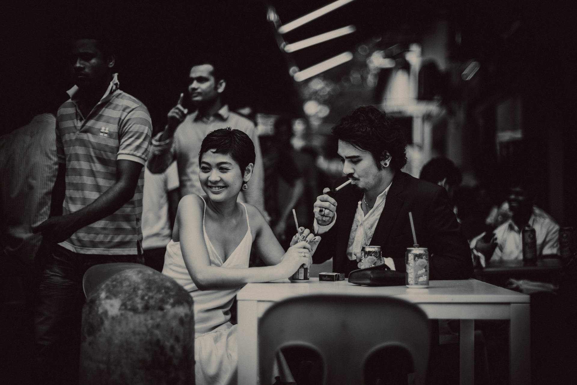 A Japanese couple enjoying a Sunday afternoon in an Indian food stall near Mustafa Centre, in black and white, from Ibuki and Emi's candid chill engagement shoot in Little India, Singapore, October 2015, Sony A7S.