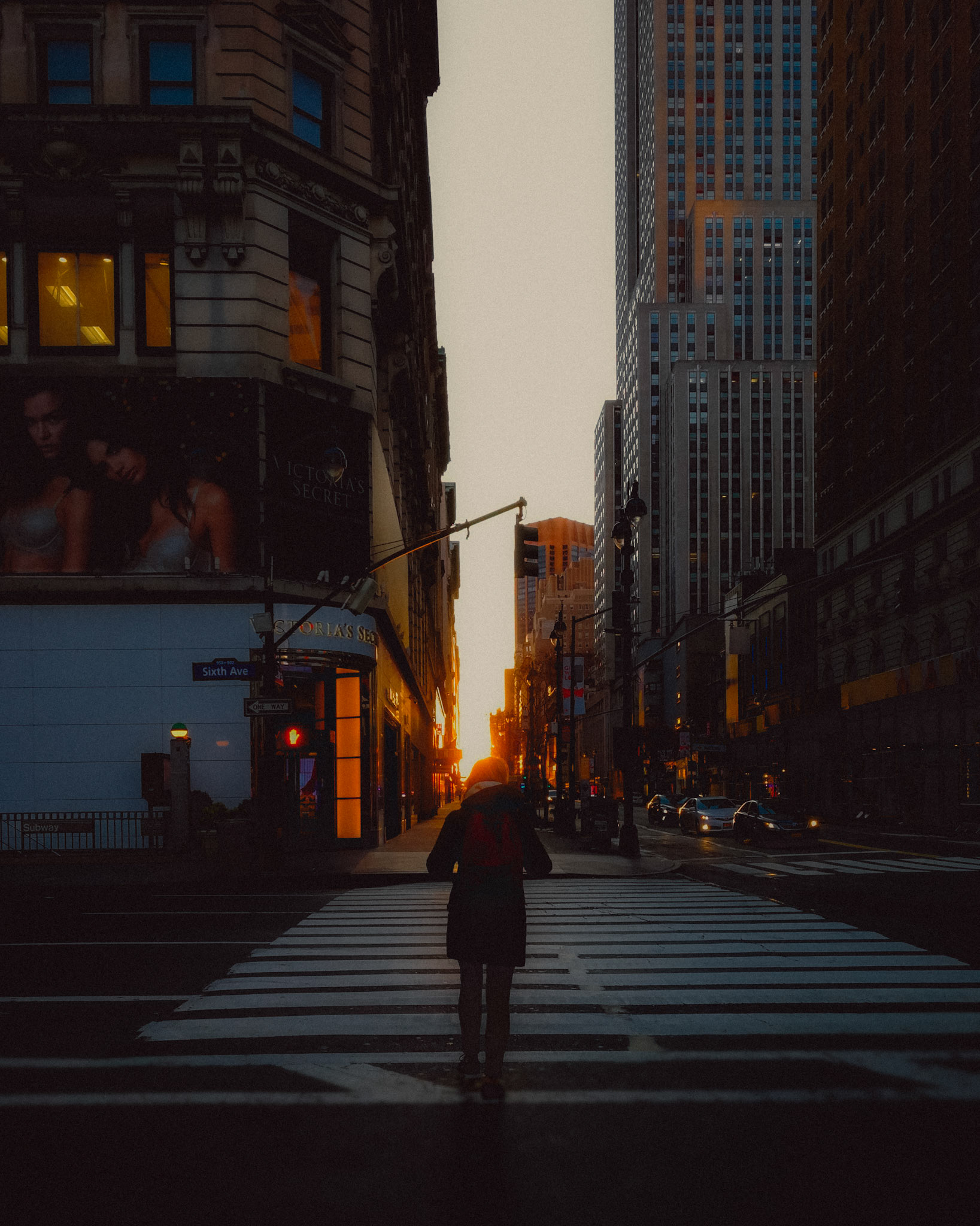 A woman crossing the street towards the sunset in Sixth Avenue, Manhattan, New York City, USA, November 2019, Huawei Mate 9 Pro.