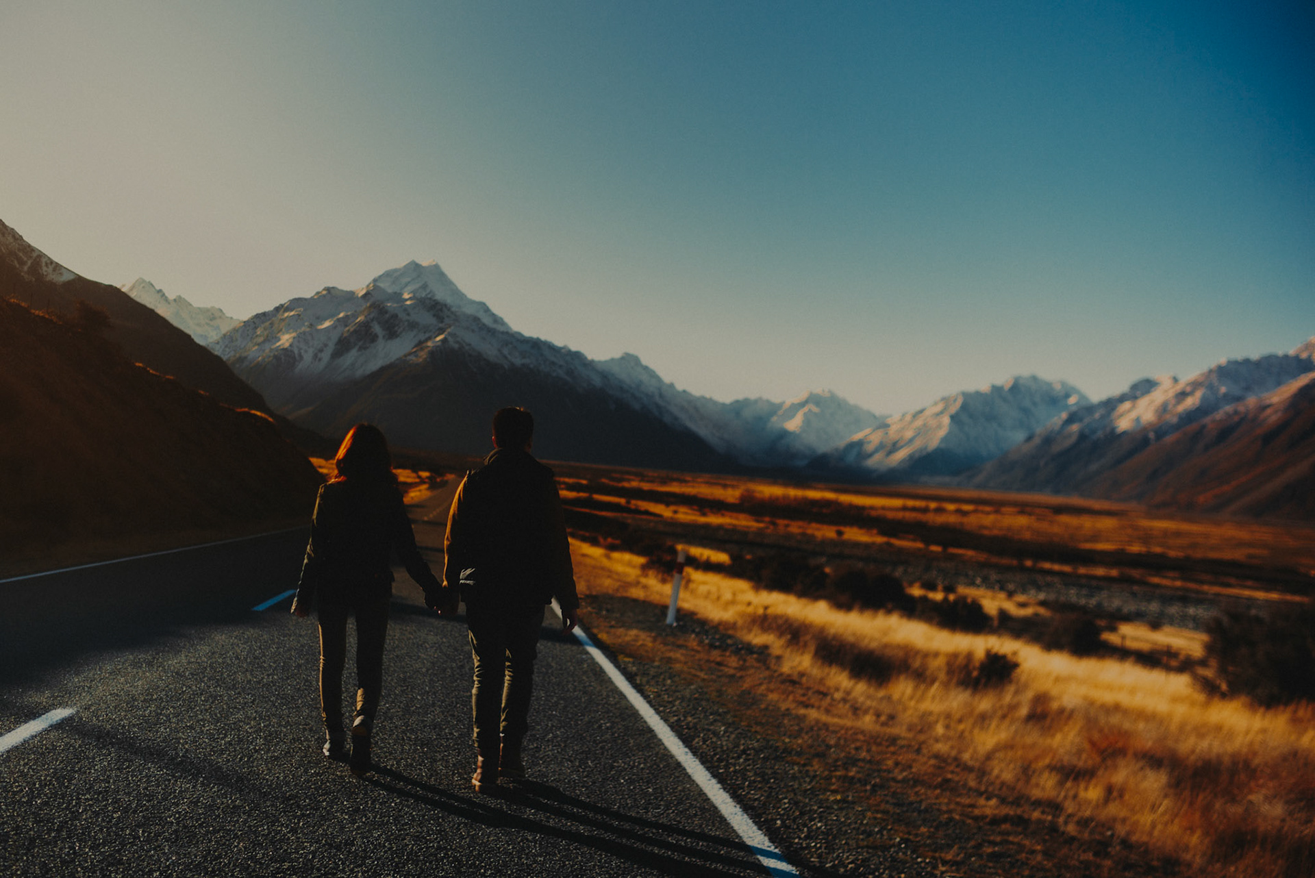 Couple adventure and travel portraits with Mount Cook's prominent snowy mountain peak and a lonely road, New Zealand, June 2017, Leica M.