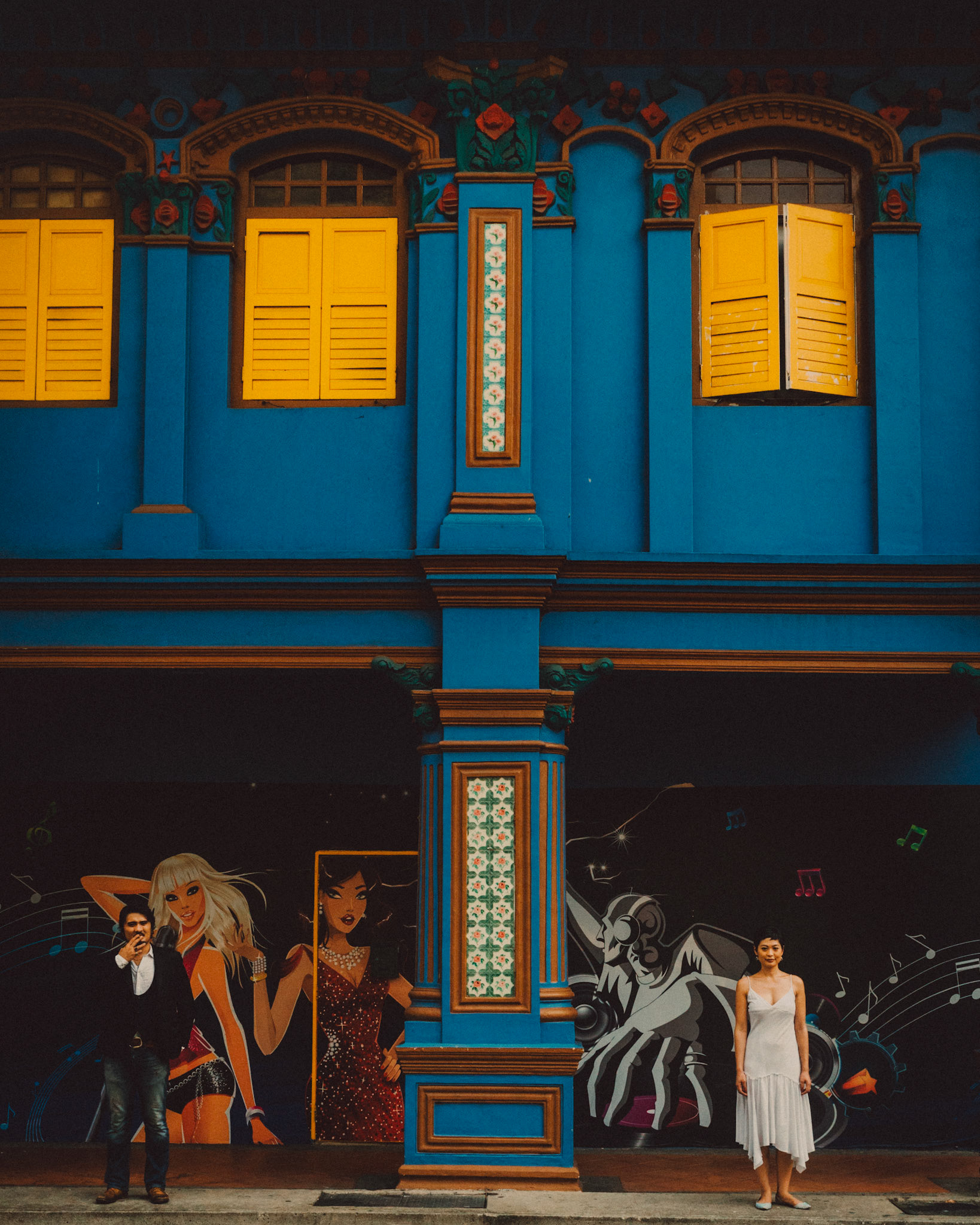 A Japanese couple standing in front of a brightly colored building, Little India, Singapore, October 2015, Sony A7S.