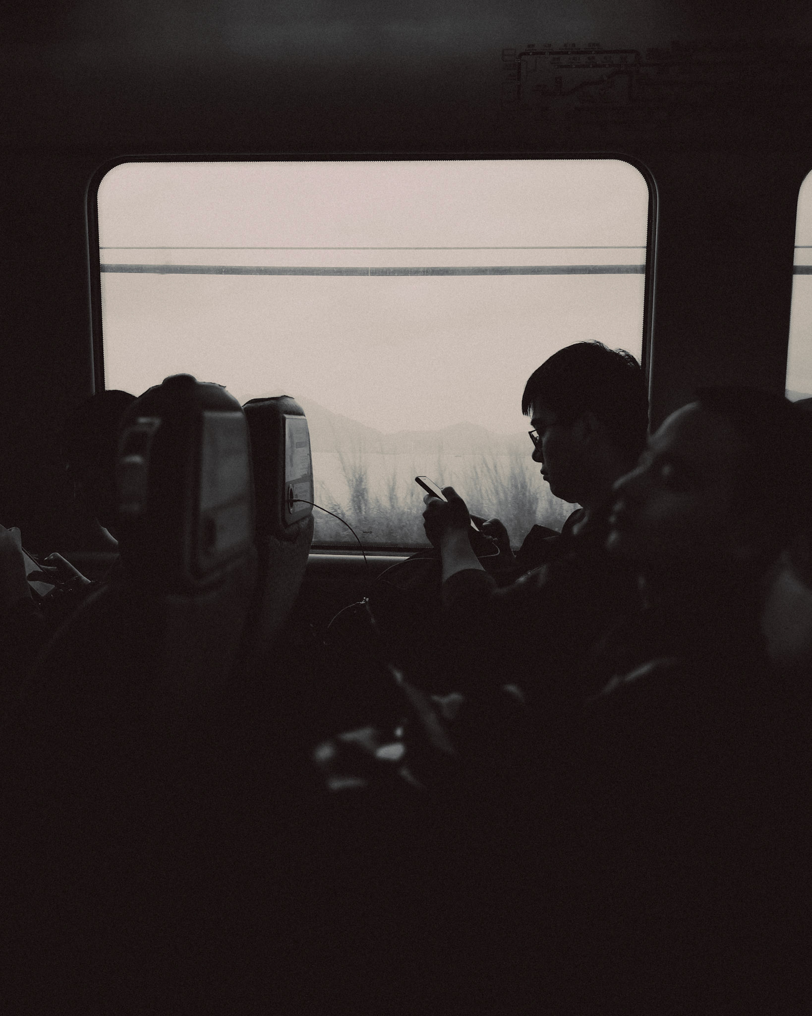A black and white photo of a commuter on the Airport Express Train, Hong Kong, April 2018, Huawei Mate 10 Pro.