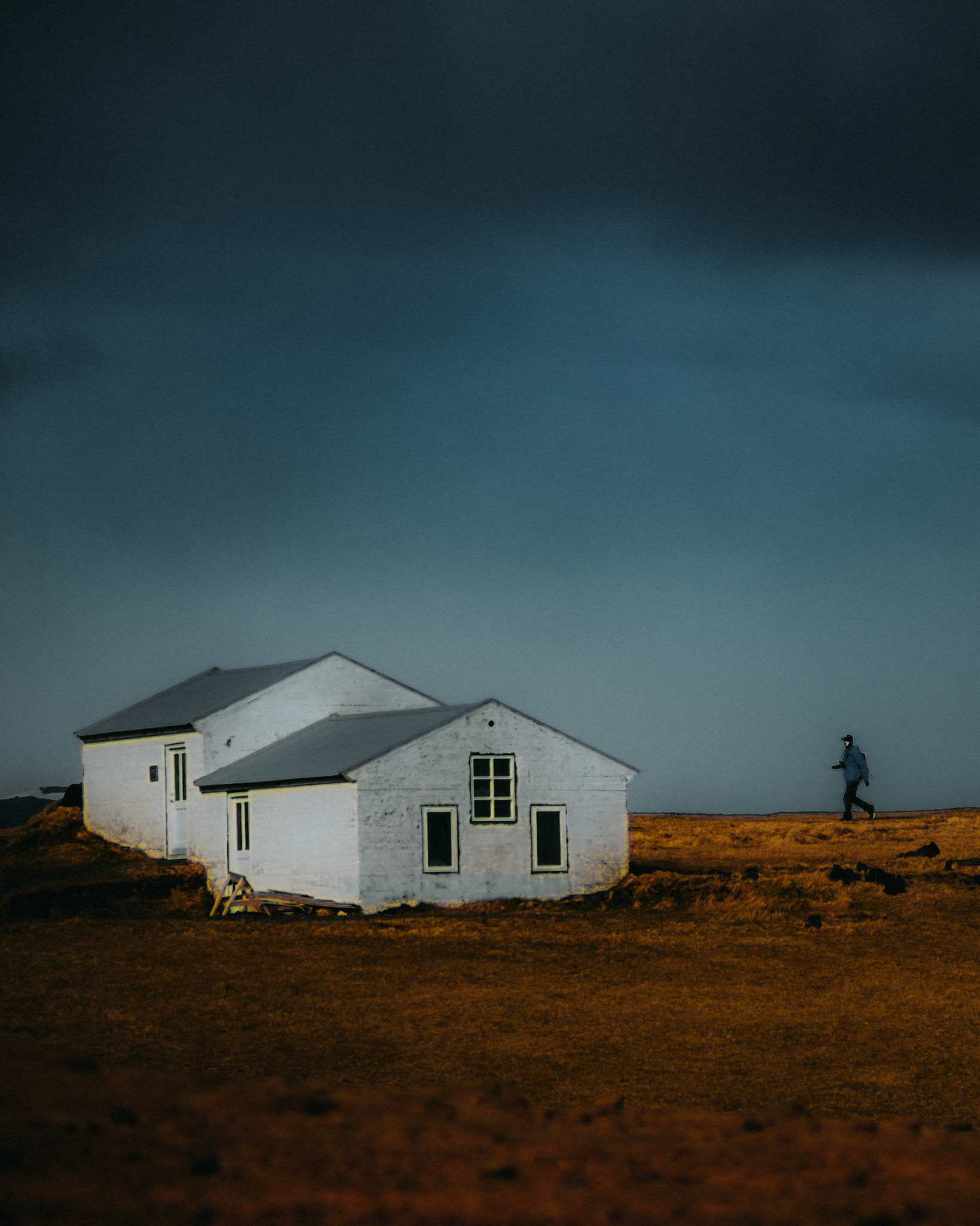 A man walking beside a lone Nordic Cottage in Dyrhólaey Viewpoint, Iceland, May 2016, Sony A7RII.