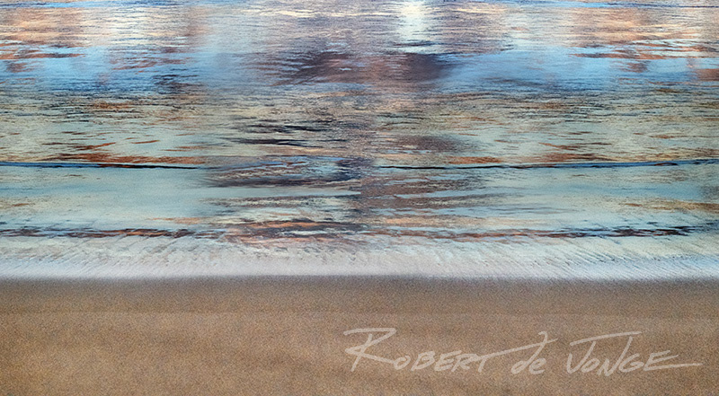 Colors reflected in the surf wash form an abstract pattern