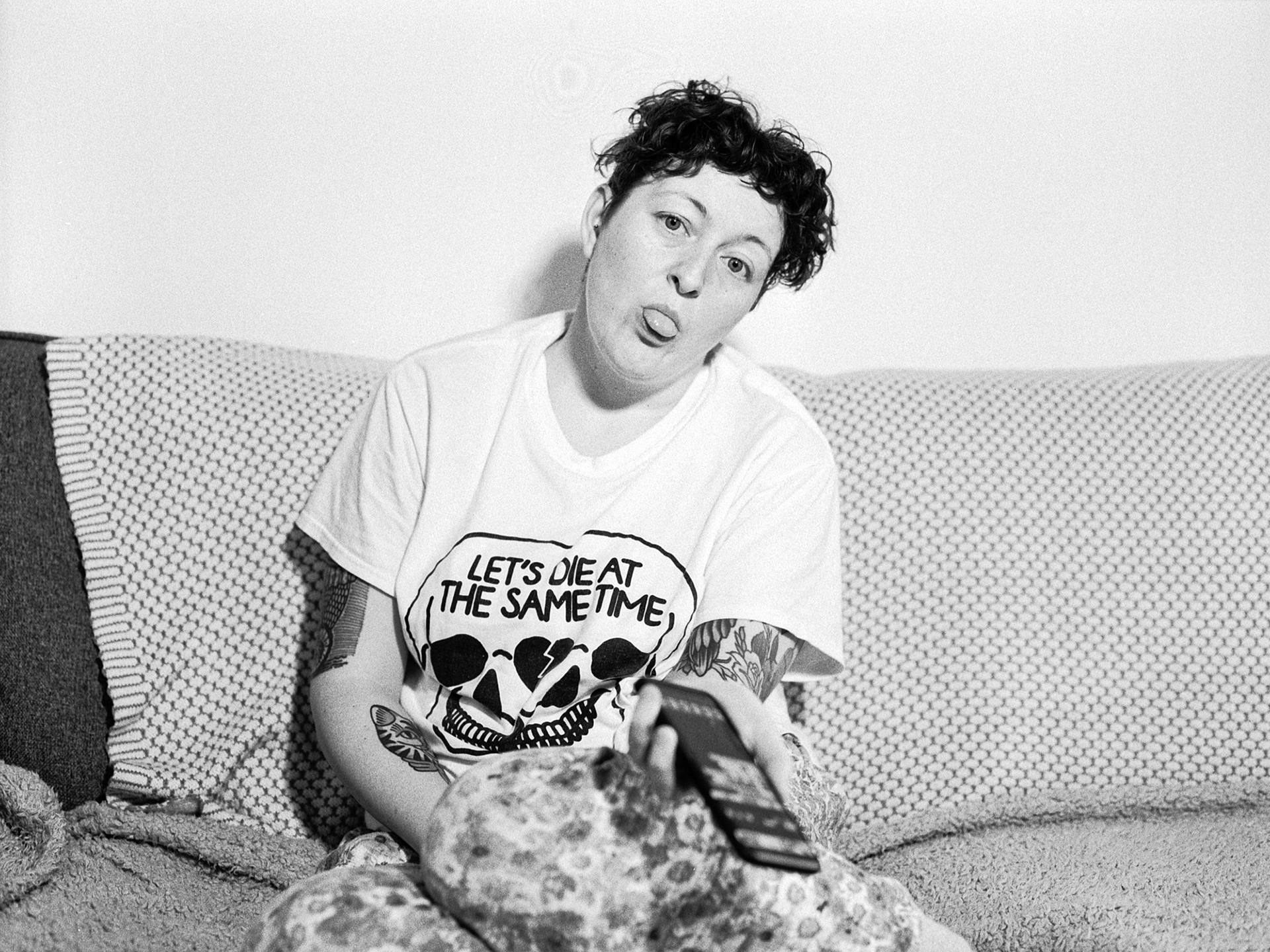 Colleen is sitting on the sofa poking her tongue out at the camera.