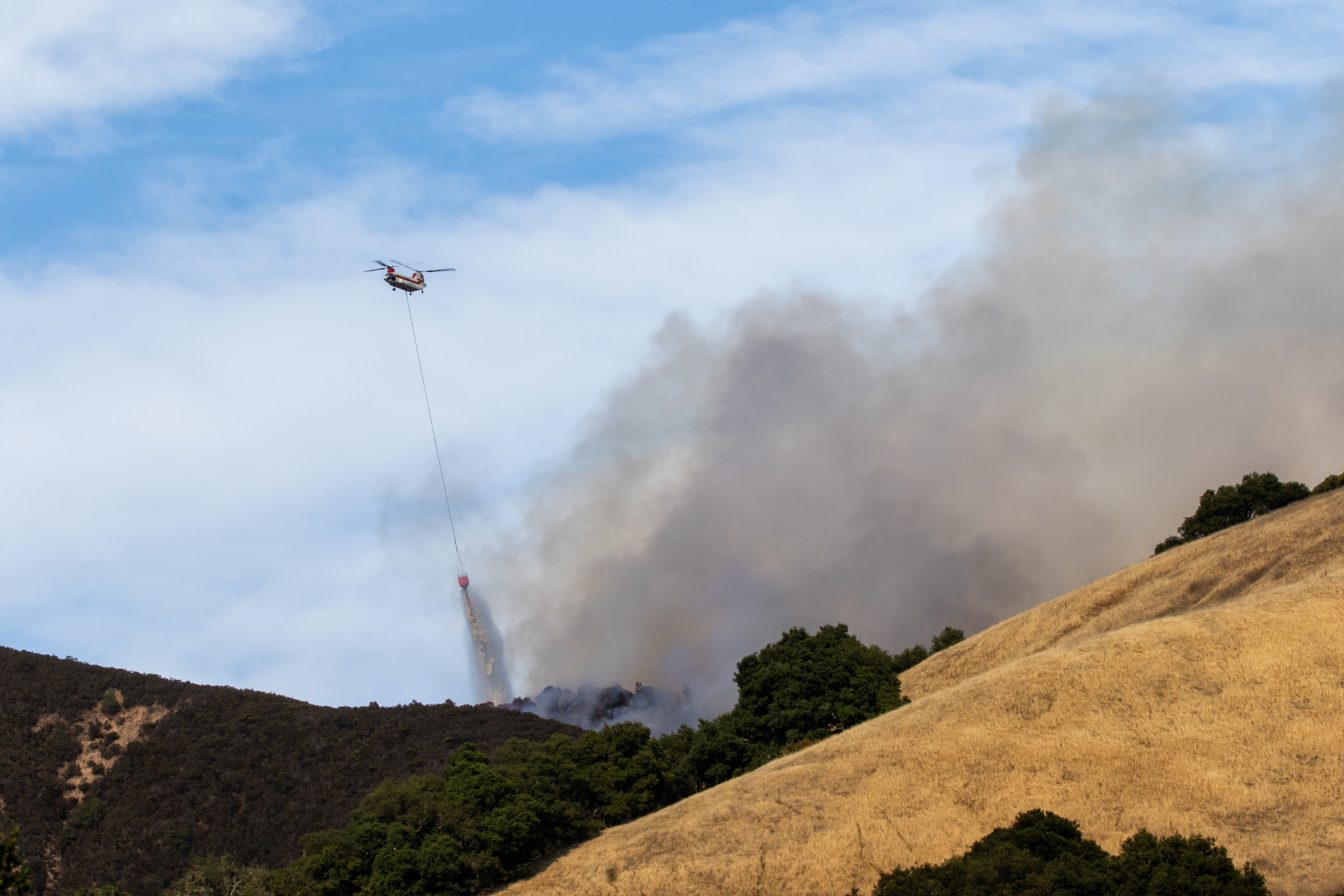 A Chinook helicopter drops water on the River fire near Mount Toro.