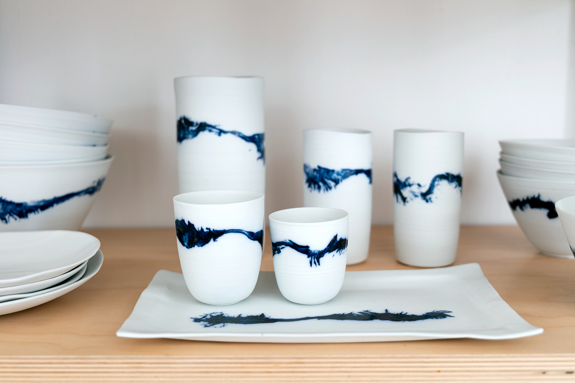 Pièces utilitaires en porcelaine non émaillées, décorée au pinceau, à l'oxyde de cobalt - Petit gobelet 19€ / Gobelet 22€ / Grand gobelet 25€ / Bol moyen 28€ / Bol grand 33€ / Plateau modèle 50€ / Plateau grand modèle 95€