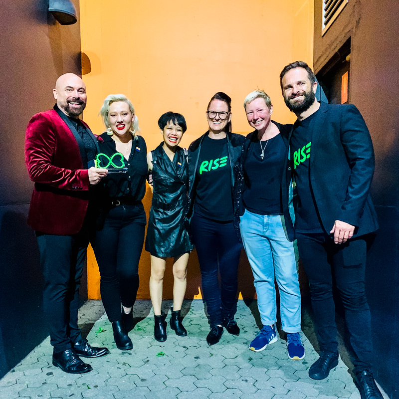Markham Lane holds the 2021 Ron Austin Award as he poses with Cassandra Loover, Emily Santiago, Mel Schwerdt, Liz Carter and Mardi Gras CEO Albert Kruger, at the conclusion of the Sydney Mardi Gras Awards in March 2021. Photo by Louis Hudson.