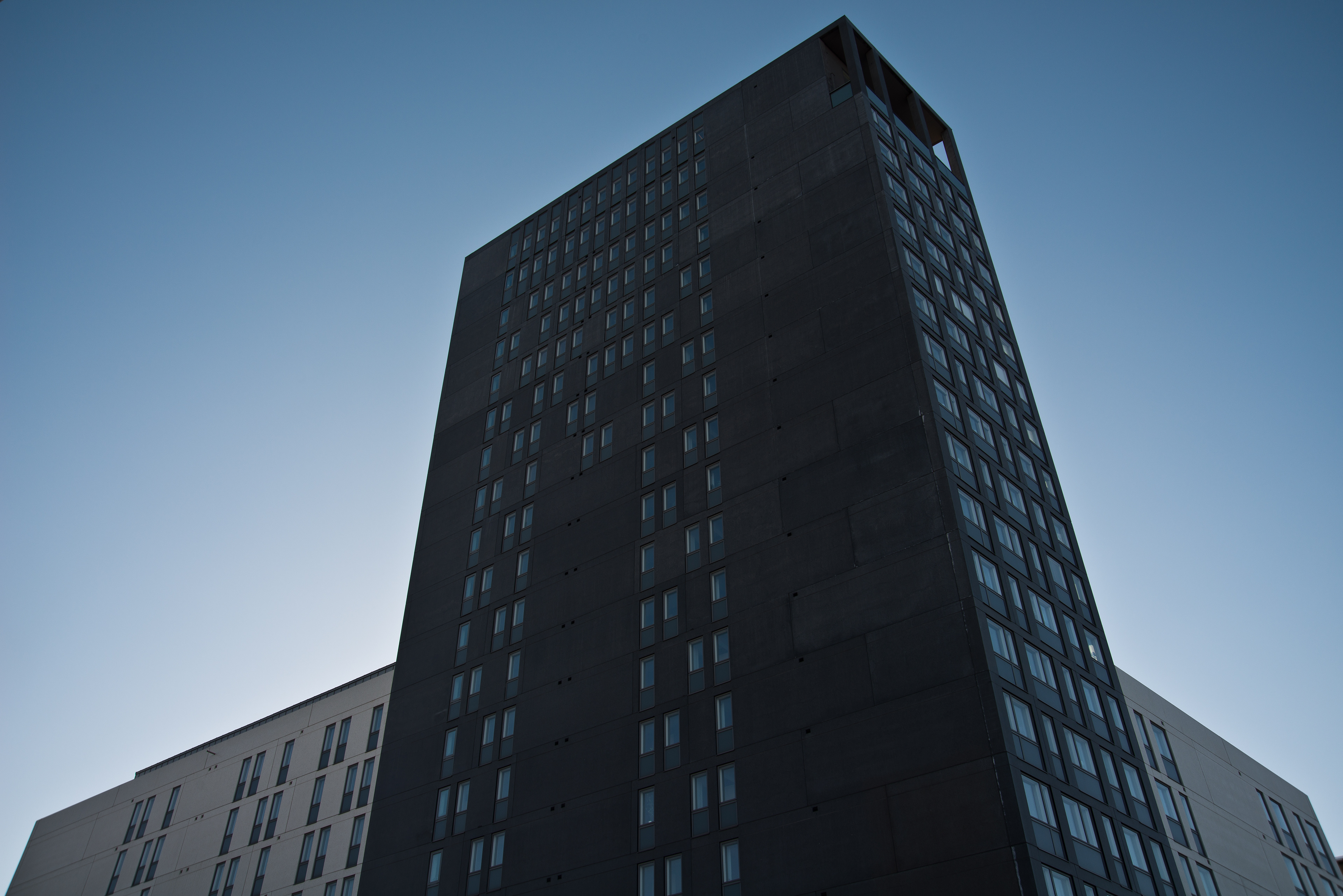 Lookig upwards at dark building with toned blue sky behind