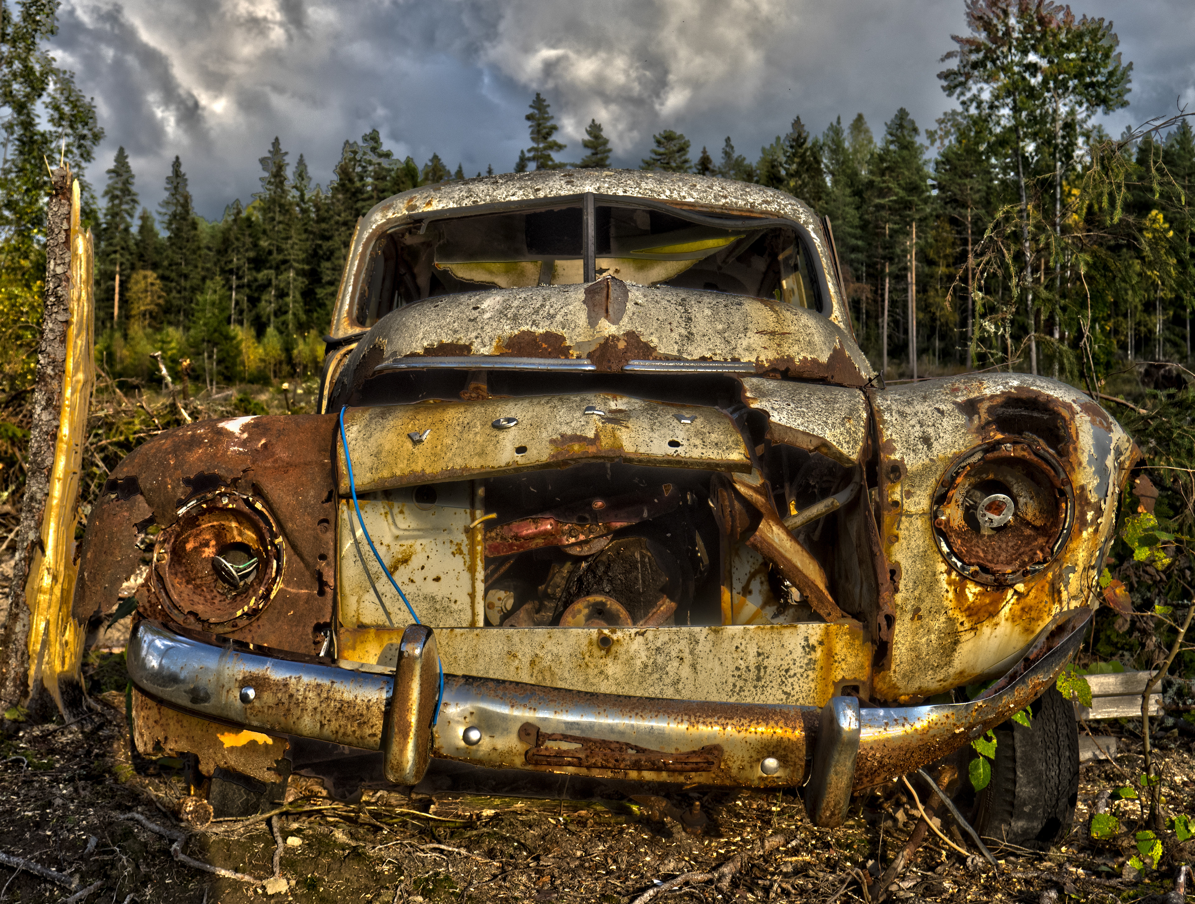 Low angled shot of front of vintage decaying rusty Volvo PV544 abandoned in the field