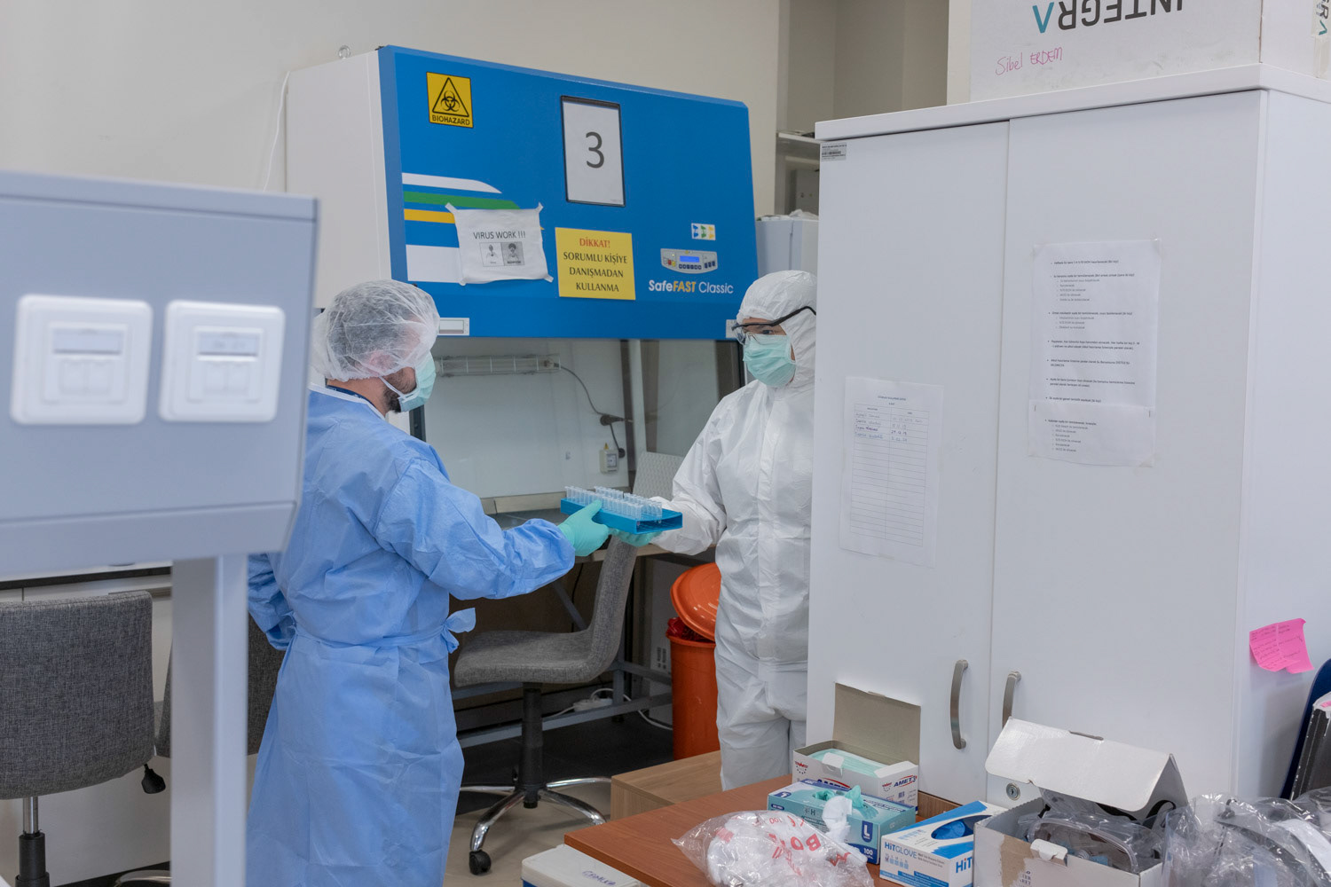 A molecular biologist wearing protective equipments on the right side of photo as she delivers the RNA samples to the another laboratory area for virus detection at a private laboratory of hospital in Istanbul on 1 May 2020.