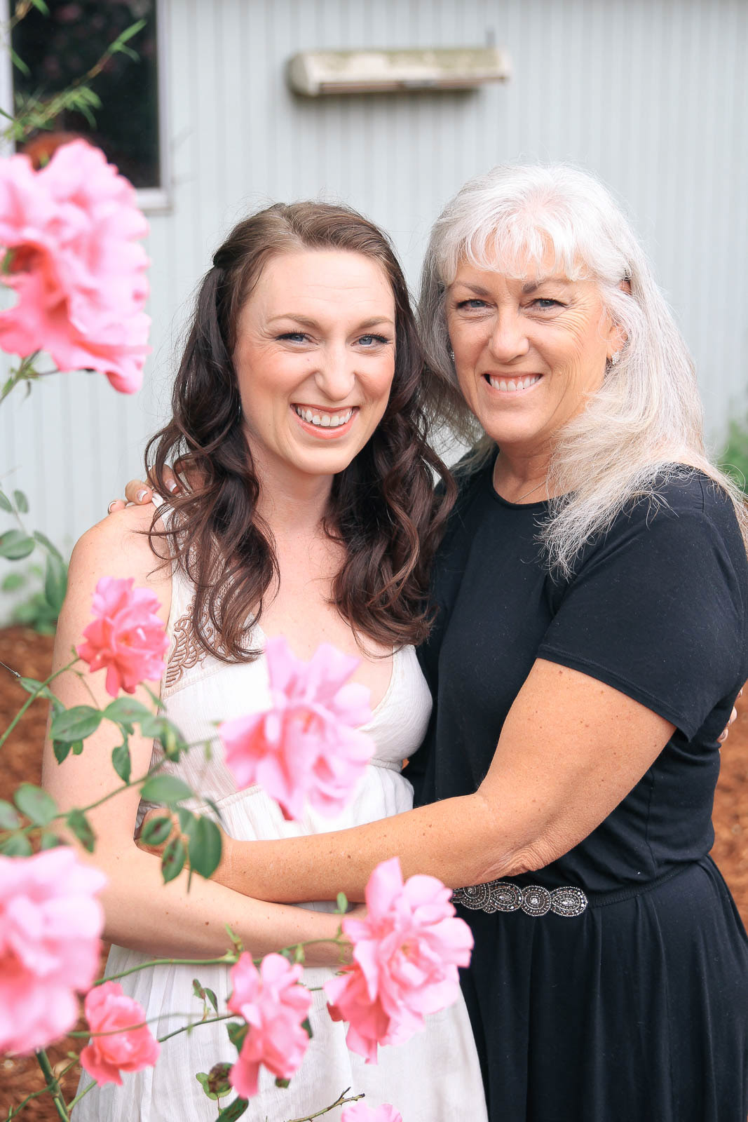 Mother and daughter holding each other for springtime portrait with flowers