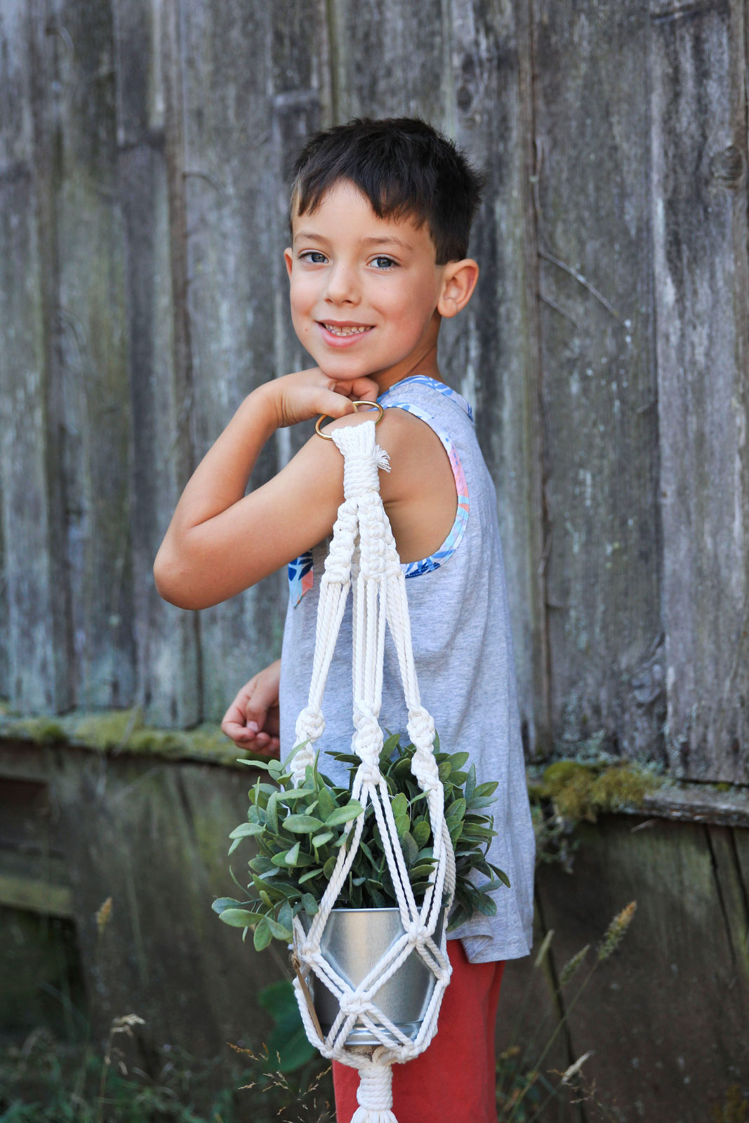 Child holds a potted plant over his shoulders