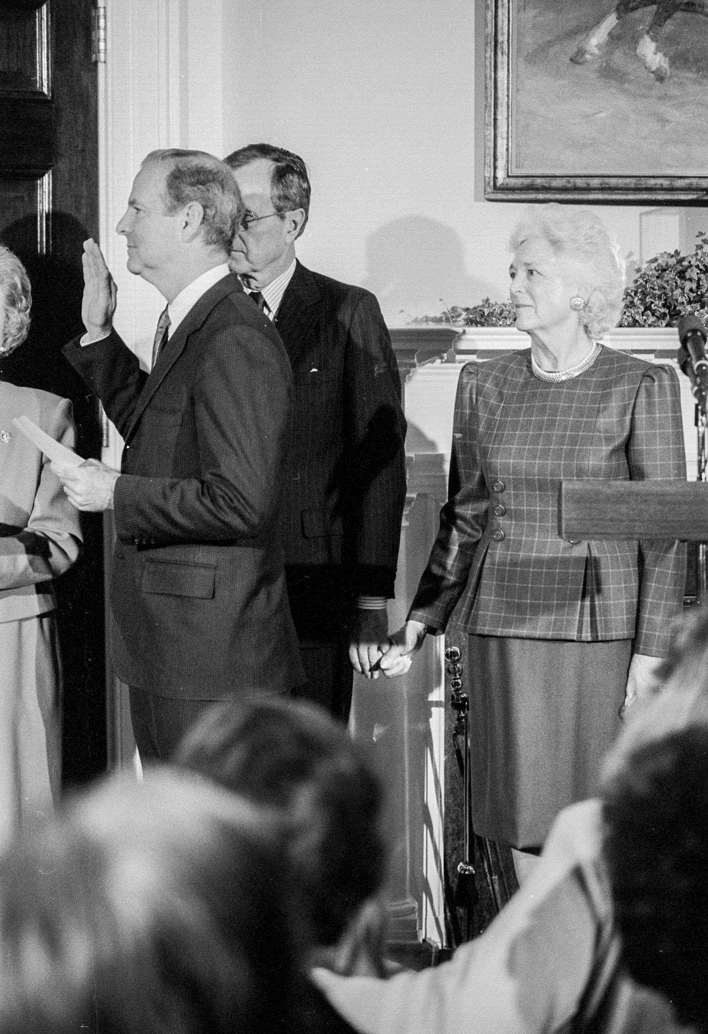 President and Barbara Bush hold hands as Secretary of State James Baker swears in Thomas Pickering as U.S. Ambassador to the United Nations, March 20, 1989.