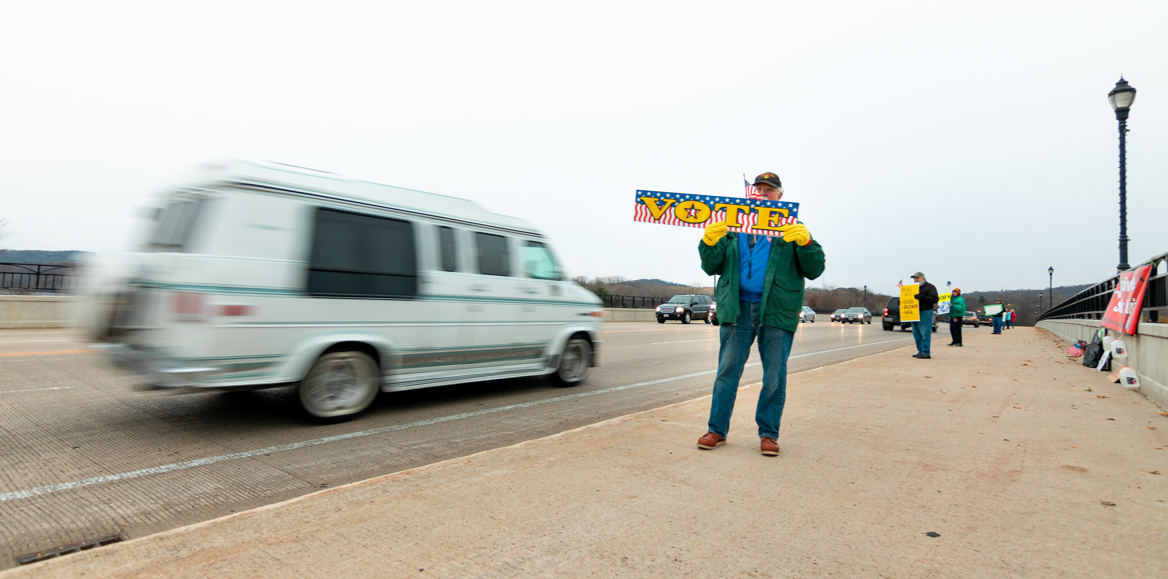 Bob Kelter holds a "vote" sign encouraging people to go vote on Tuesday.