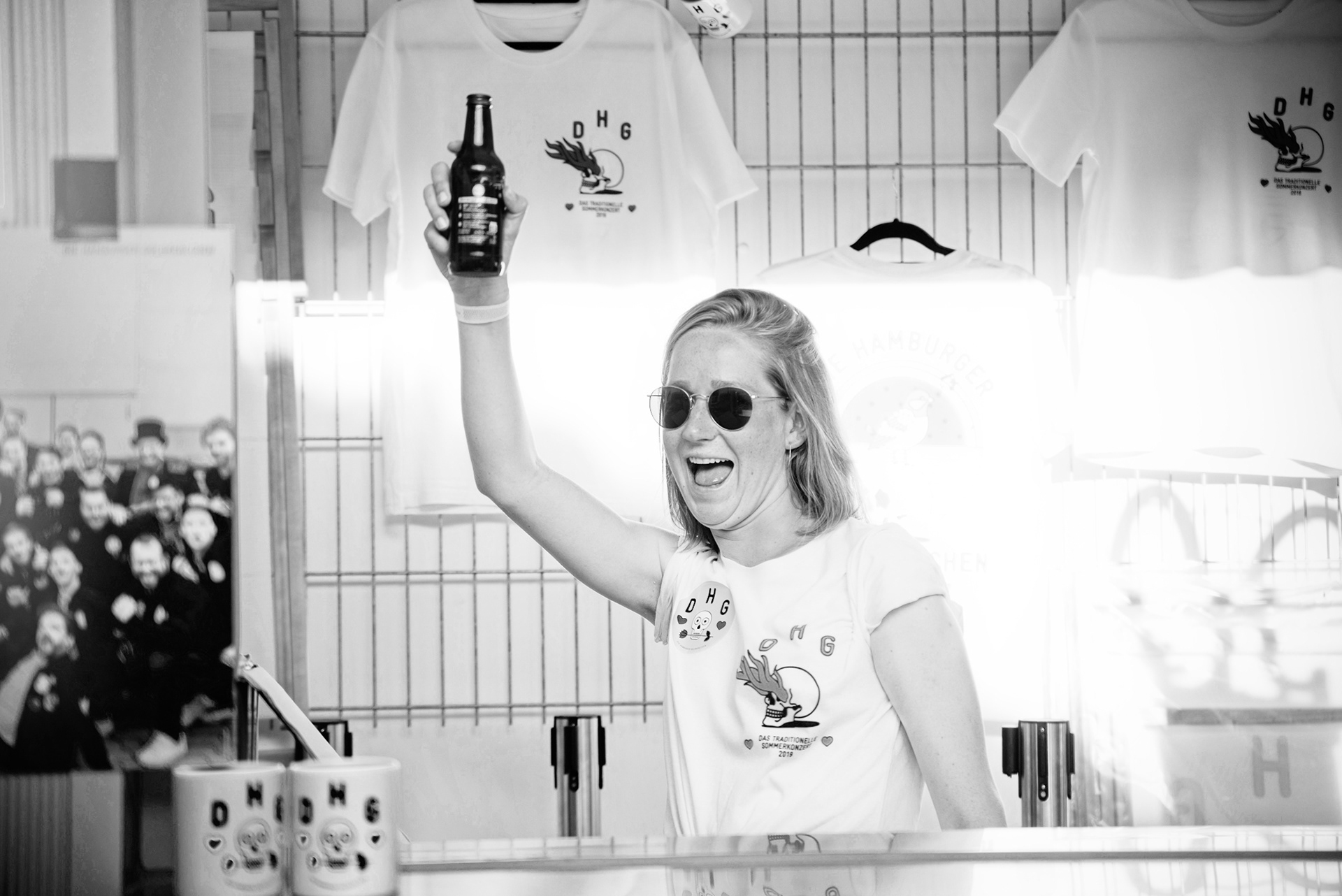 frau grüßt fröhlich mit flasche