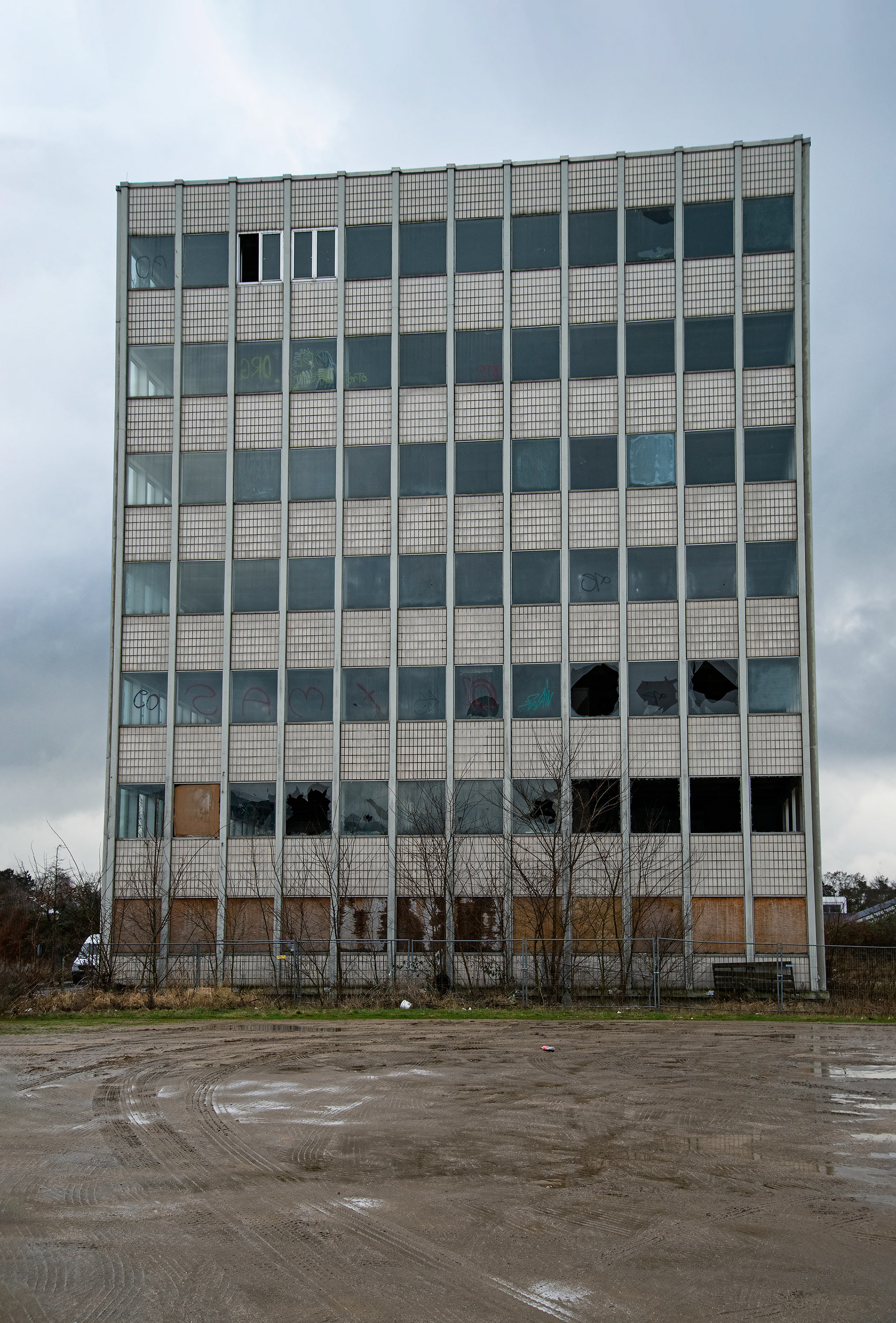 Abrissgebäude im Industriegebiet - Büroschluss für immer. Mit Schreibtisch und Papieren haben sie das Weite gesucht. Wer weiß, wohin. Graue Hülle mit leeren Fenstern auf schlammigem Grund. Andere kamen, auf der Suche nach Abenteuer und Schutz. Stilles Warten auf den letzten Akt.