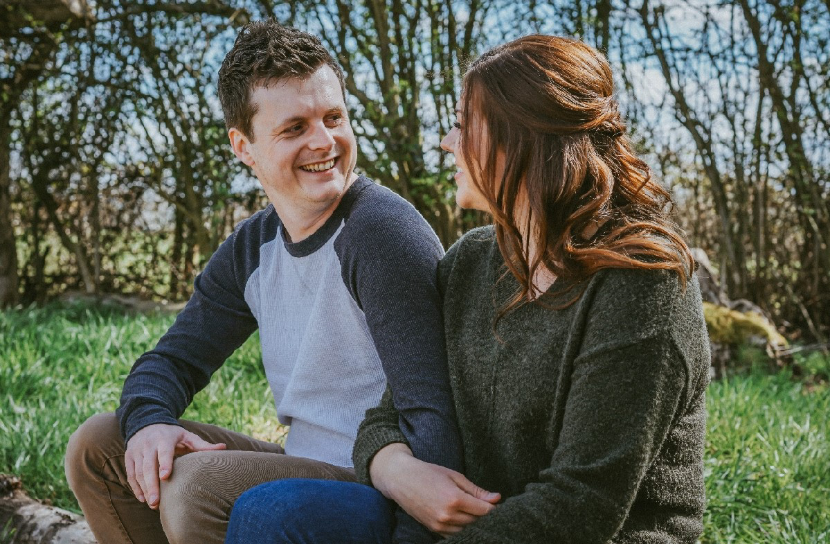 candid photo of happily engaged couple at woodland at pre wedding photo shoot session with david lefebvre a wedding portrait and product photographer from buckinghamshire uk the photo has been edited with warm and deep colouring