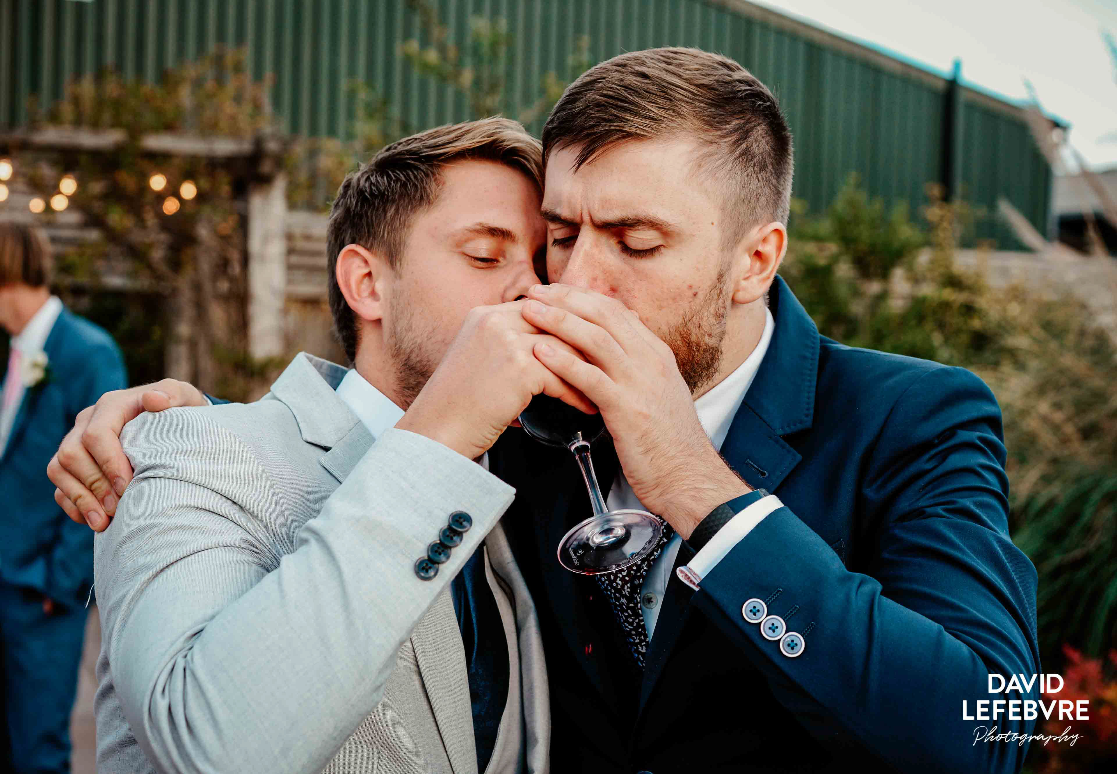 guys in suits sharing wine glass together at owen barn house wedding venue