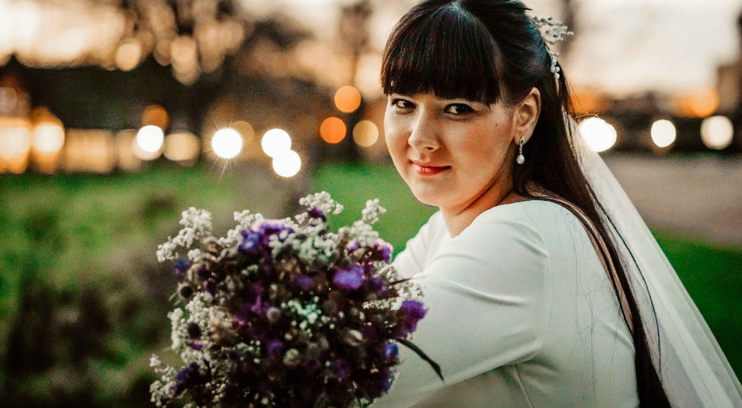 smiling beautiful russian bride with flowers in golden hour leant on fence after intimate december covid wedding in oxford with buckinghamshire photographer david lefebvre