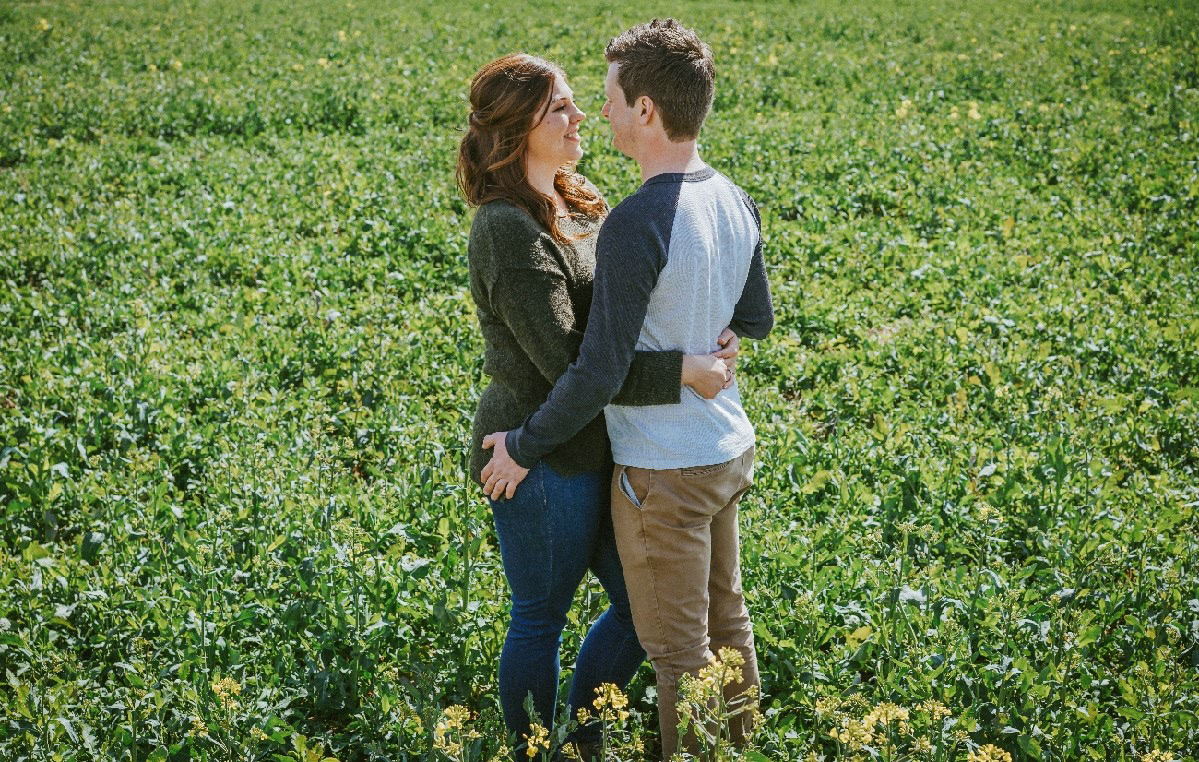 socially distanced photographer david lefebvre photo of couple close up of couple smiling holding each other in rapeseed field in swanbourne uk on pre wedding engagement photo shoot session