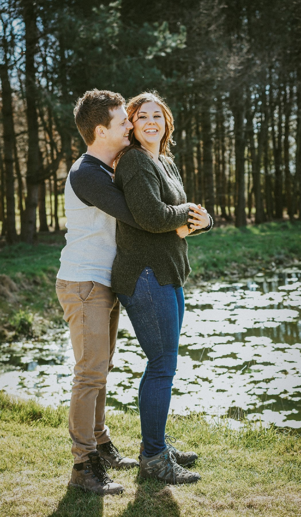 soon to be groom holds soon to be bride in the sunlight by the lake at endeavour woodland wedding venue near milton keynes with candid photographer david lefebvre from milton keynes