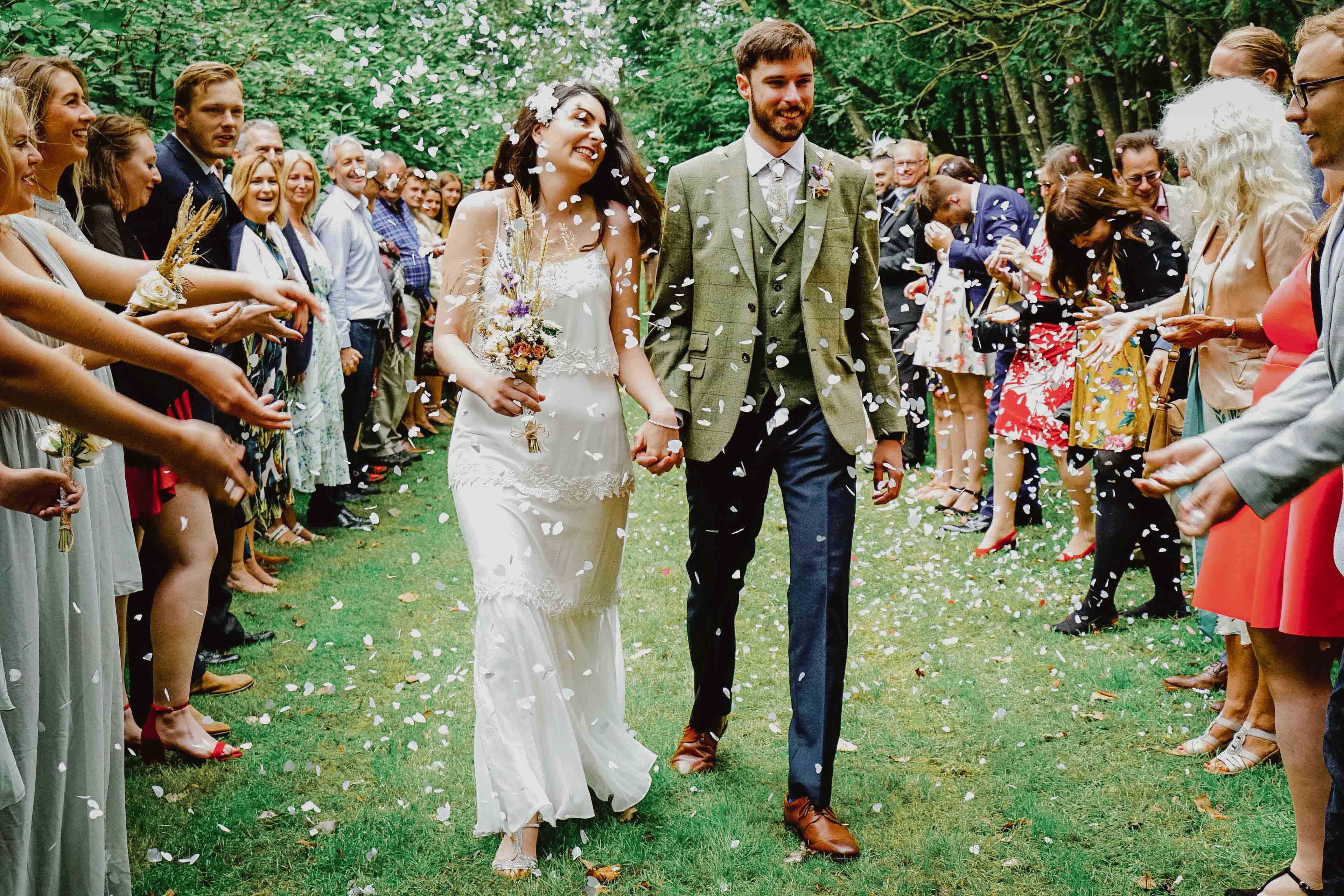 young bride and groom smiling and walking down confetti aisle at endeavour woodland wedding venue with photographer david lefebvre in swanbourne buckinghamshire uk