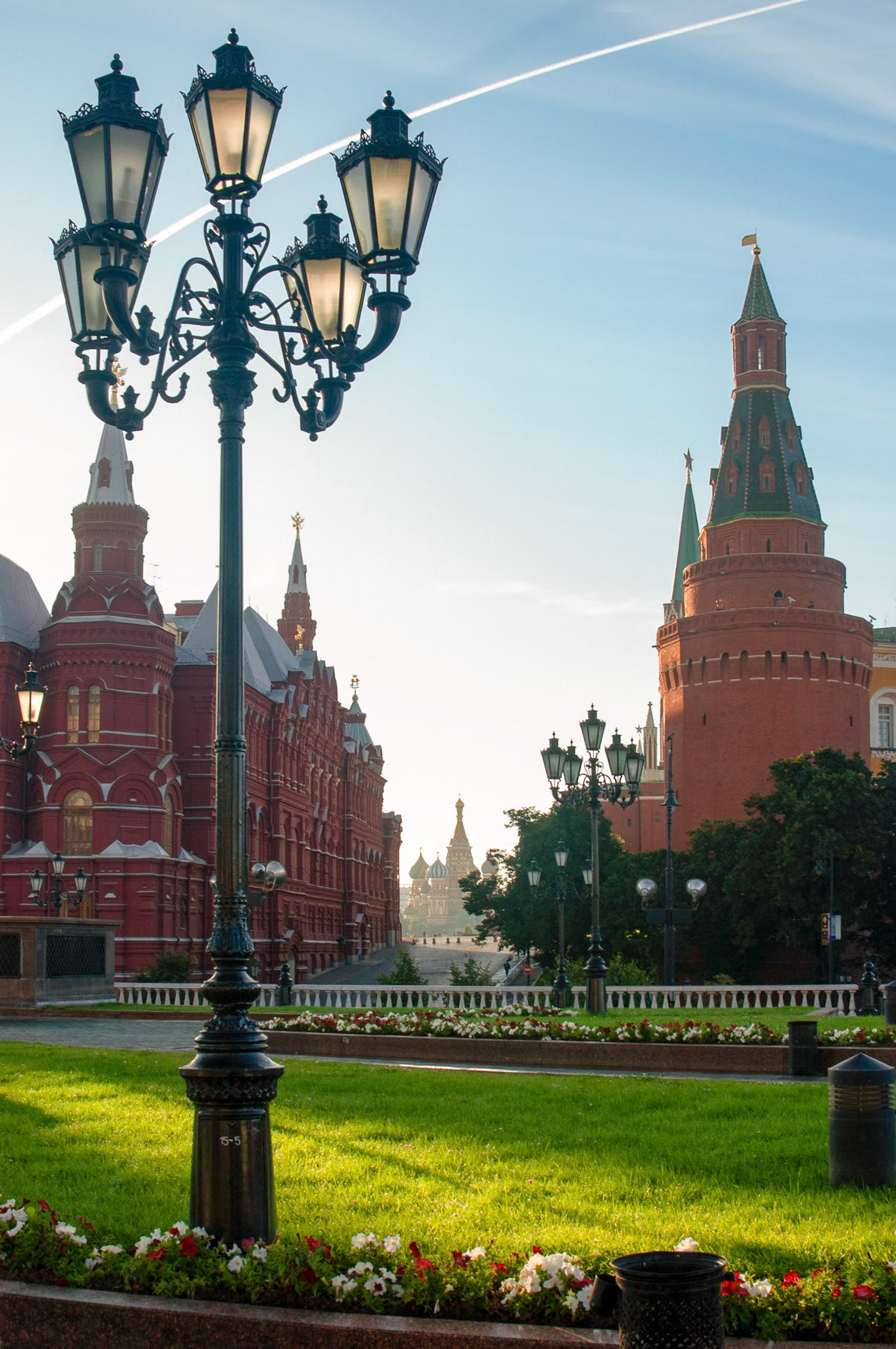 View of Red Square and St. Basil's Cathedral from Manezhnaya Ploshchad as seen through the corridor between the State Historical Museum and the Corner Arsenal Tower of the Kremlin wall with a lamppost in the foreground.