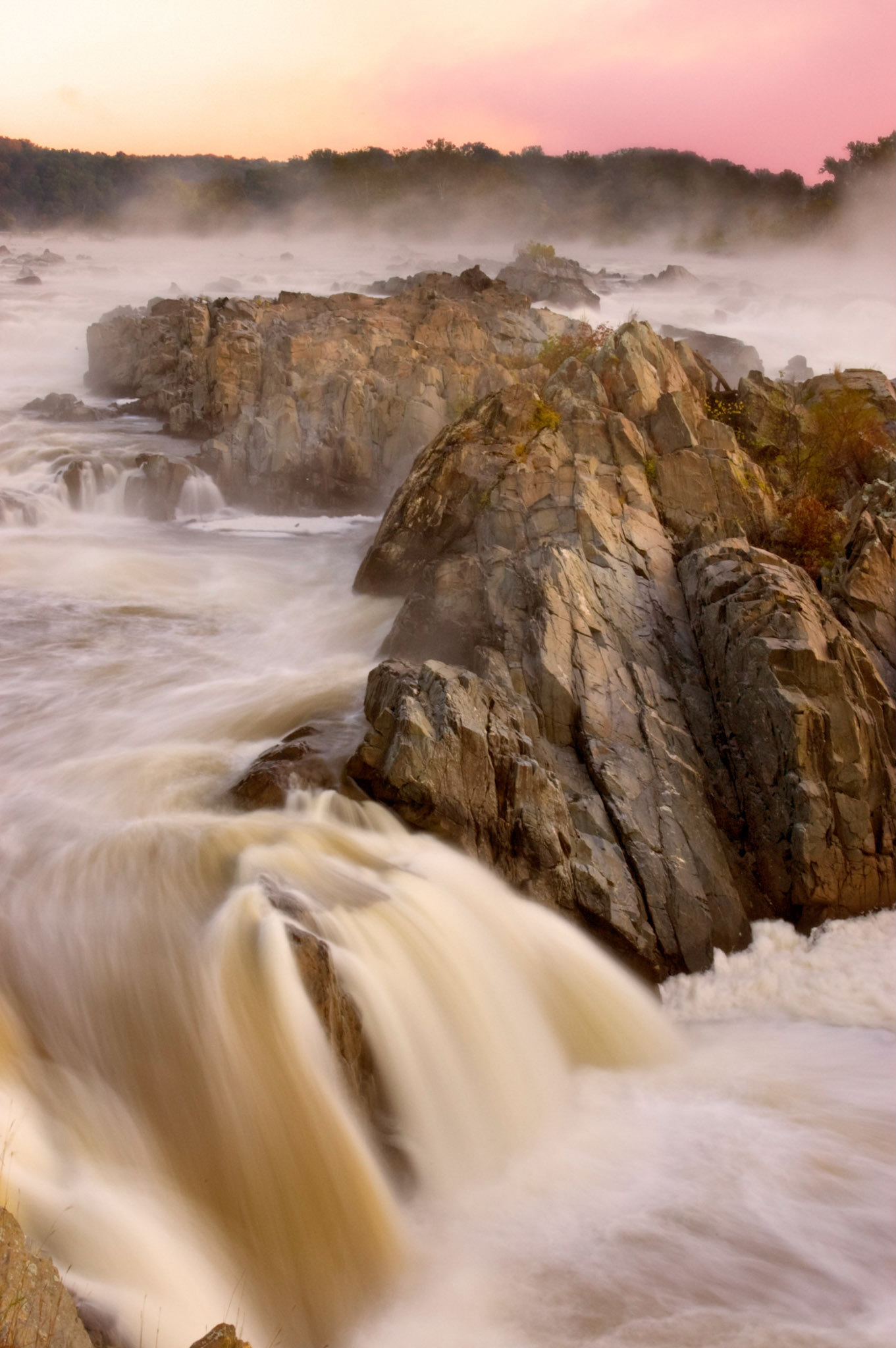 A dawn view of a misty, rocky waterfall at Great Falls National Park in Virginia.