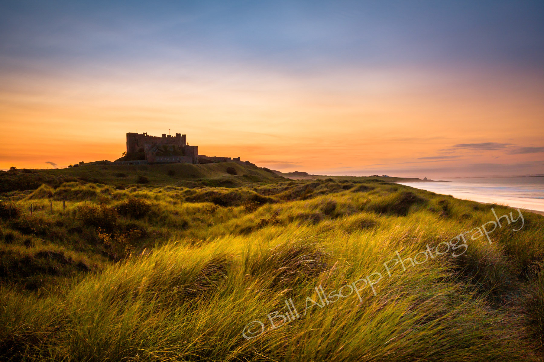 Bamburgh castle and dunes at sunset.