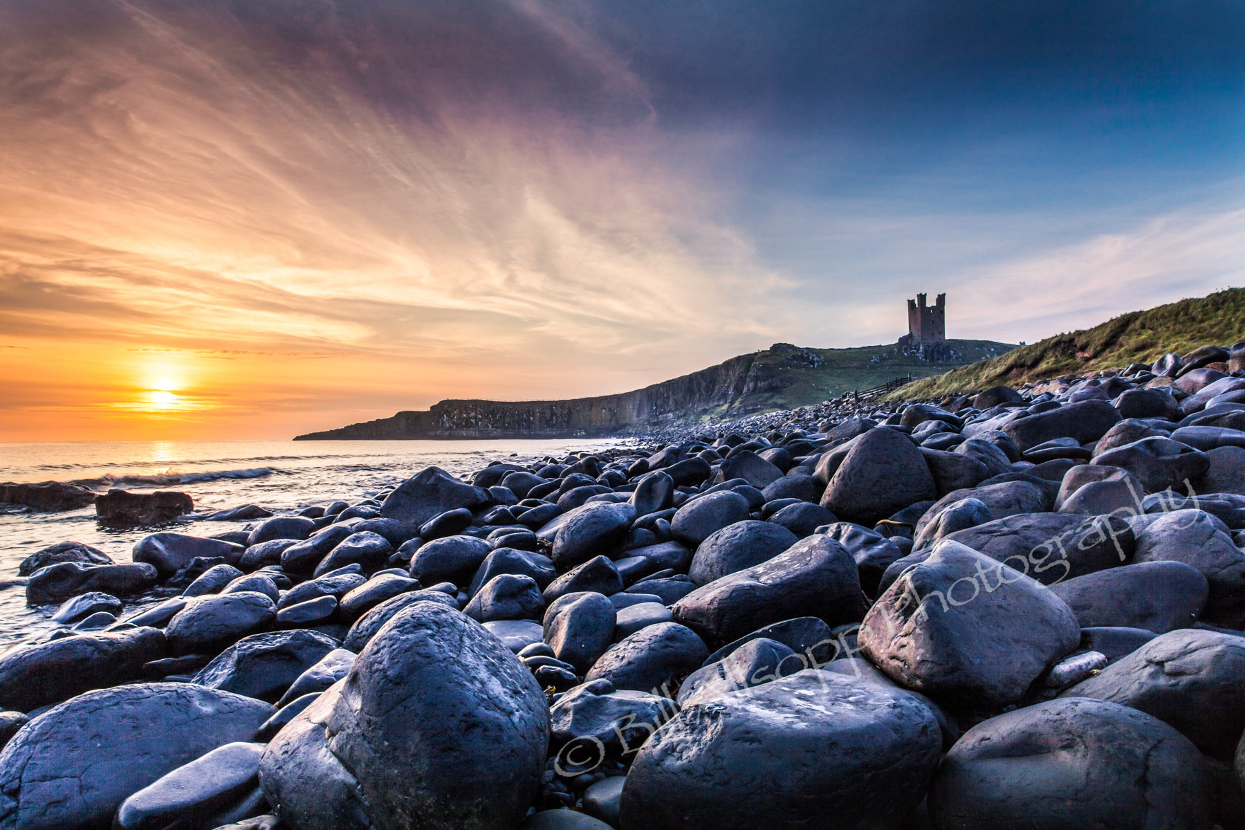Dunstanburgh castle in Northumberland at dawn.