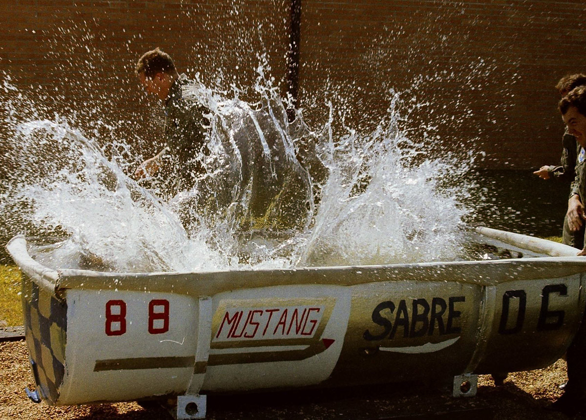 "In a tedious, mob-rule ritual pushed onto all of us..., student pilots returning from initial solos were involuntarily baptized in the dunk tank, a Petri dish of dirty swill, culturing next to the chute shop."