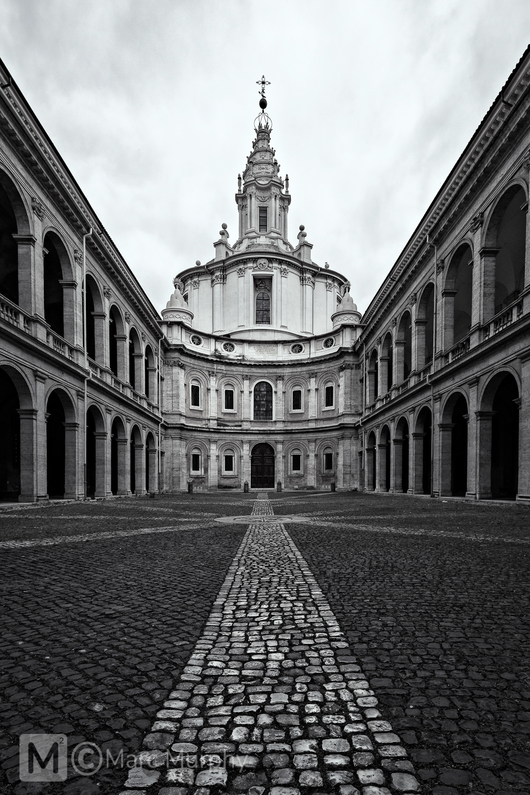 Black and White St. Ivo alla Sapienza Church Courtyard in Rome Italy with a Stone Path Leading to a Spiral Steeple and Cross