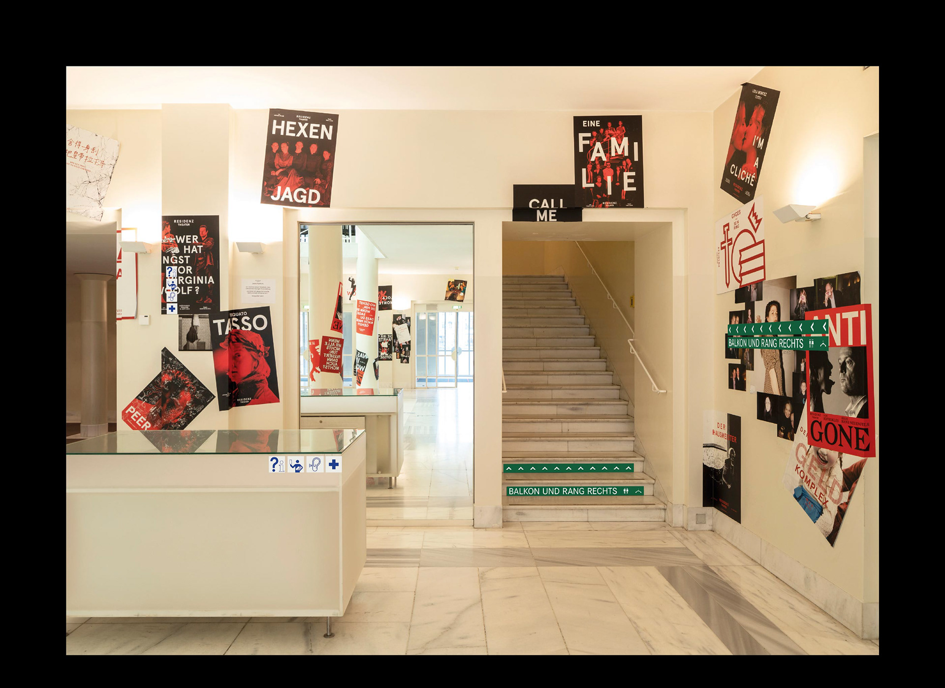 Leitstreifen und Informationsschilder im Foyer des Münchner Residenztheaters an der Wand, an Treppenstufen und am Informationstresen