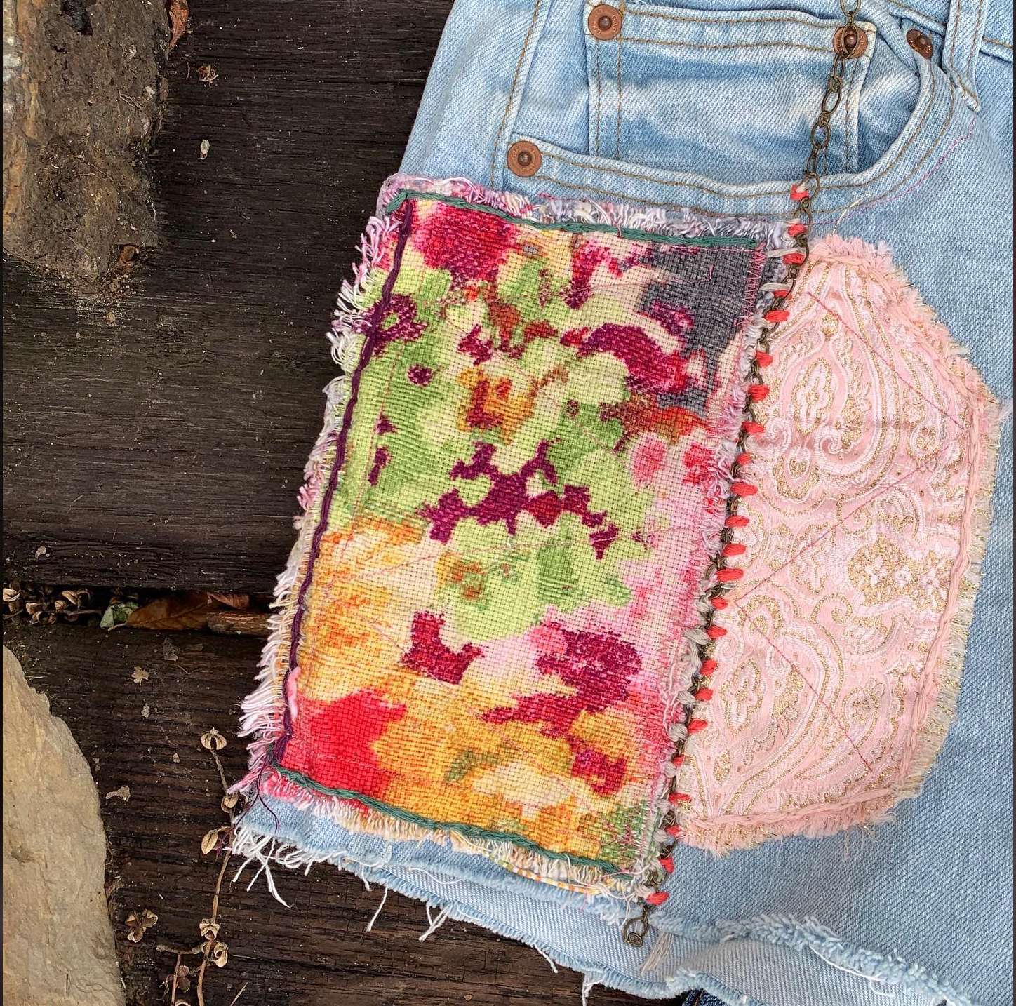 Fabric, chain and embroidery on jean shorts.