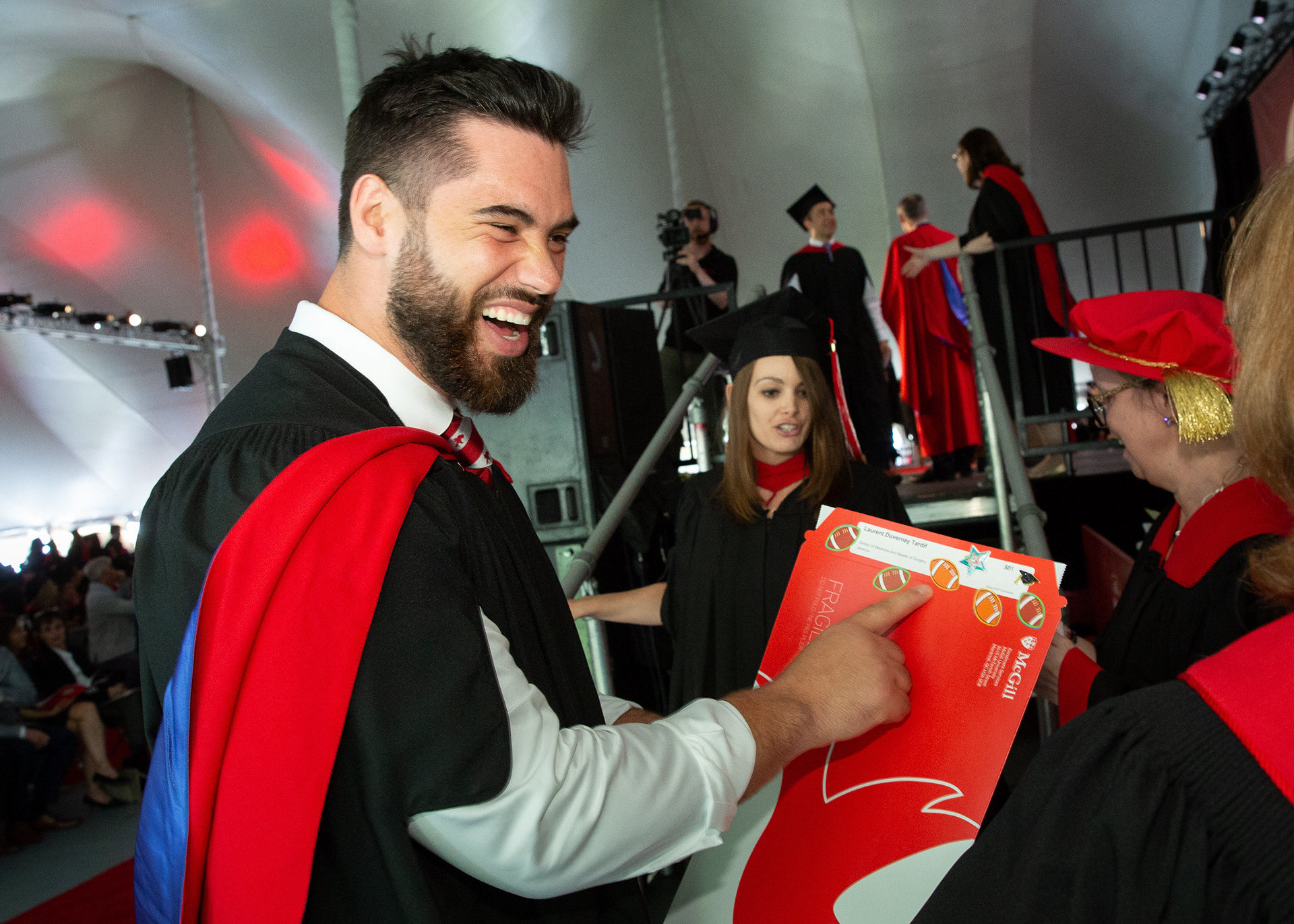 A visibly delighted Laurent Duvernay-Tardif discovers little football stickers on his diploma after crossing the convocation stage in 2018. The McGill MD went on to pad his resumé with “Superbowl Champion” in 2019.