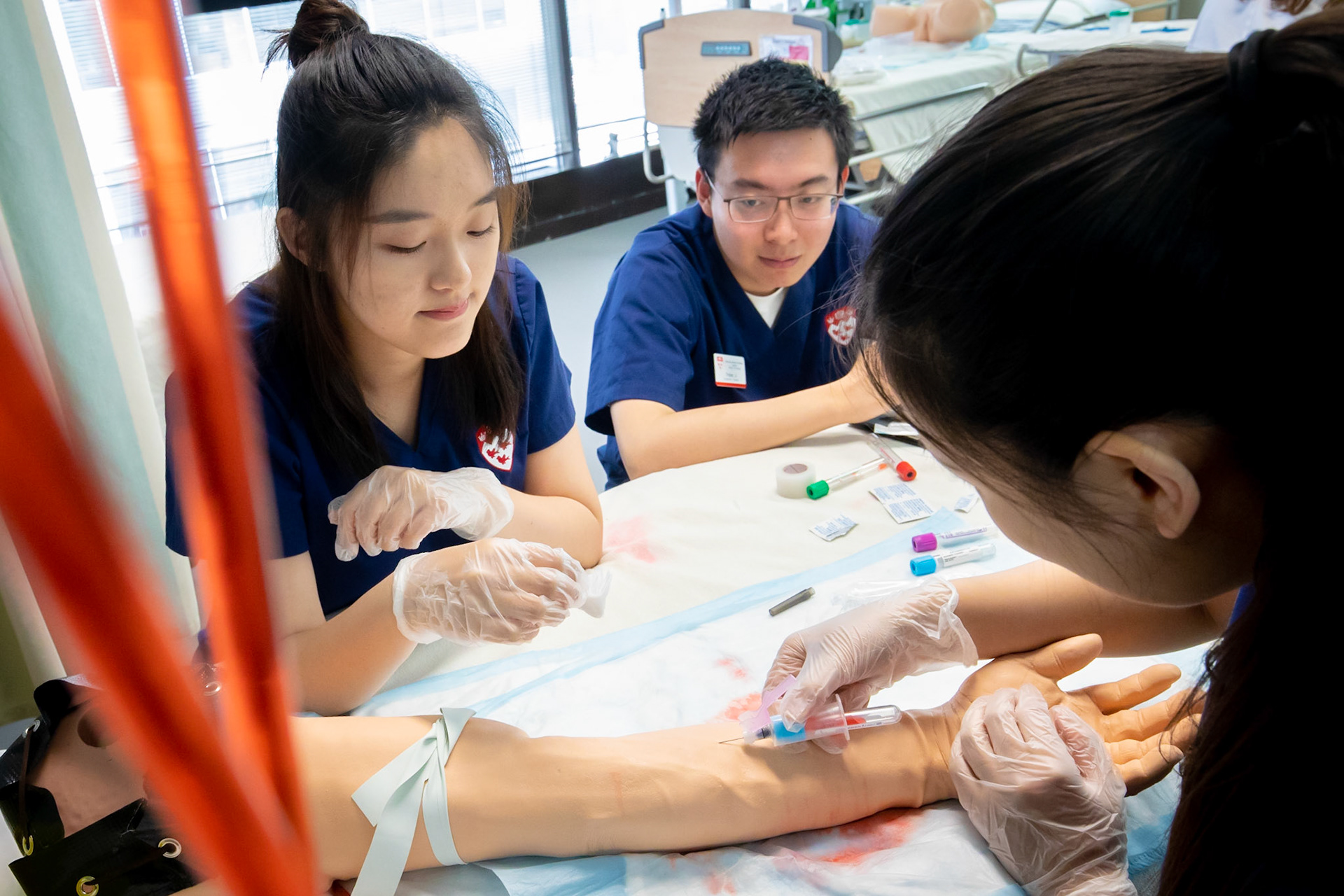 Students practice drawing blood from a high-tech mannequin arm at the Ingram School of Nursing.  June 2019.