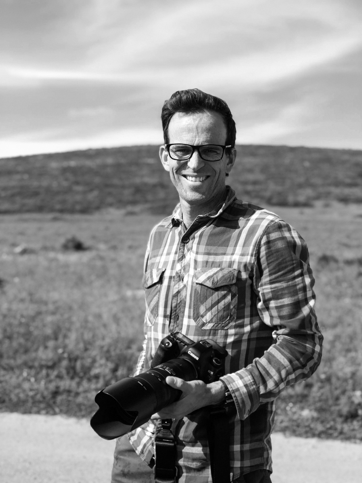 Julian Goldswain,portrait, man holding camera in hand,field in the background,West Coast National Park