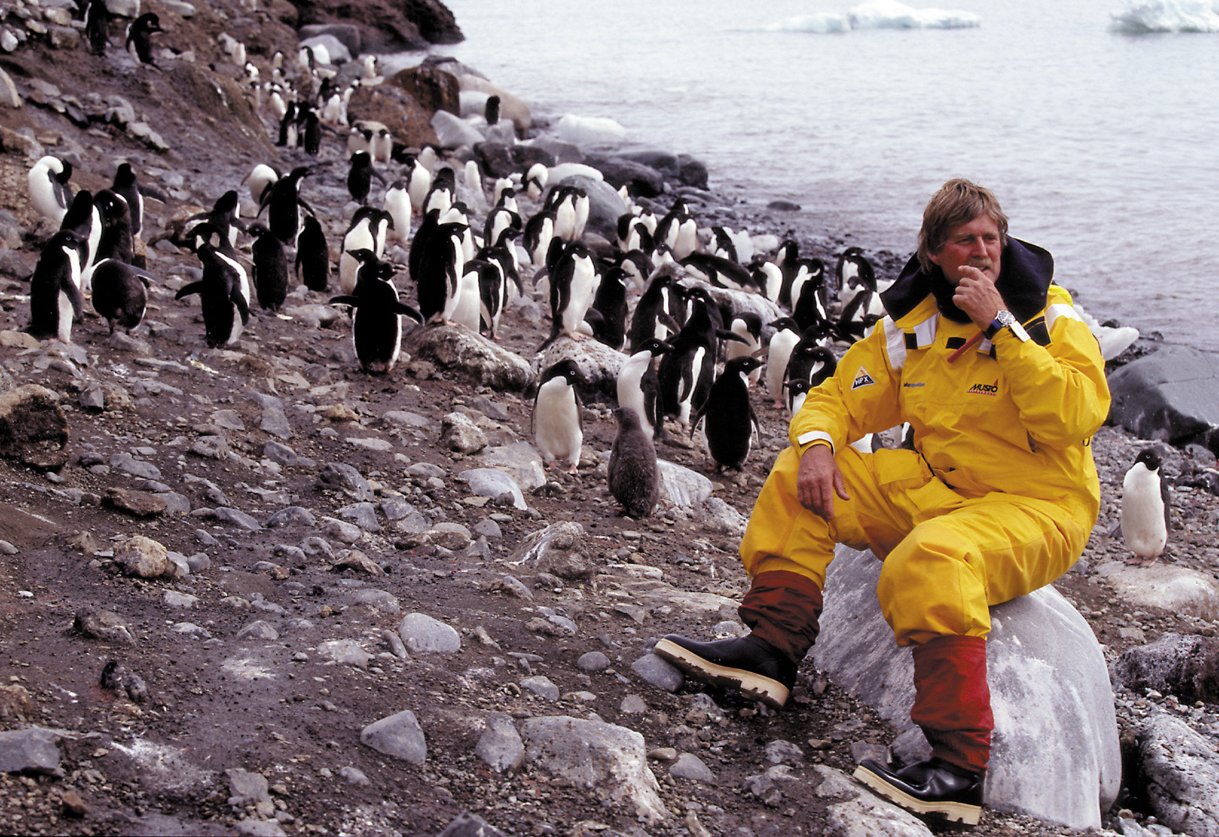 Sir Peter in Antarctica smiling alongside some sweet Adélie penguins! Credit - Ivor Wilkins.