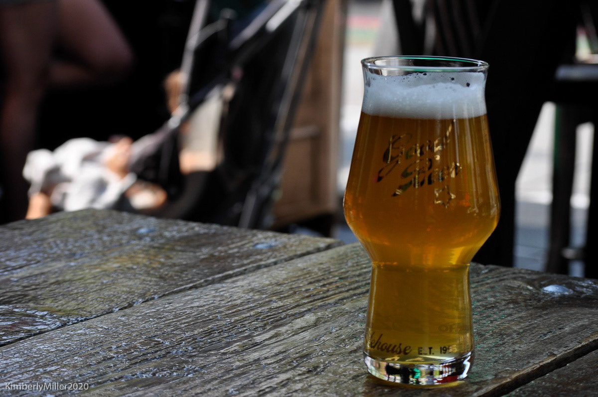 Liquid Gold: Hazy IPA, I liked the color and texture of the beer and smoothness of glass on the rough table, 20200906, Boise Idaho, Miller, Sam and I like to spend time outside in Boise walking around. Camera Settings: Nikon D500, ISO 200, 55mm, f/7.1, 1/200s