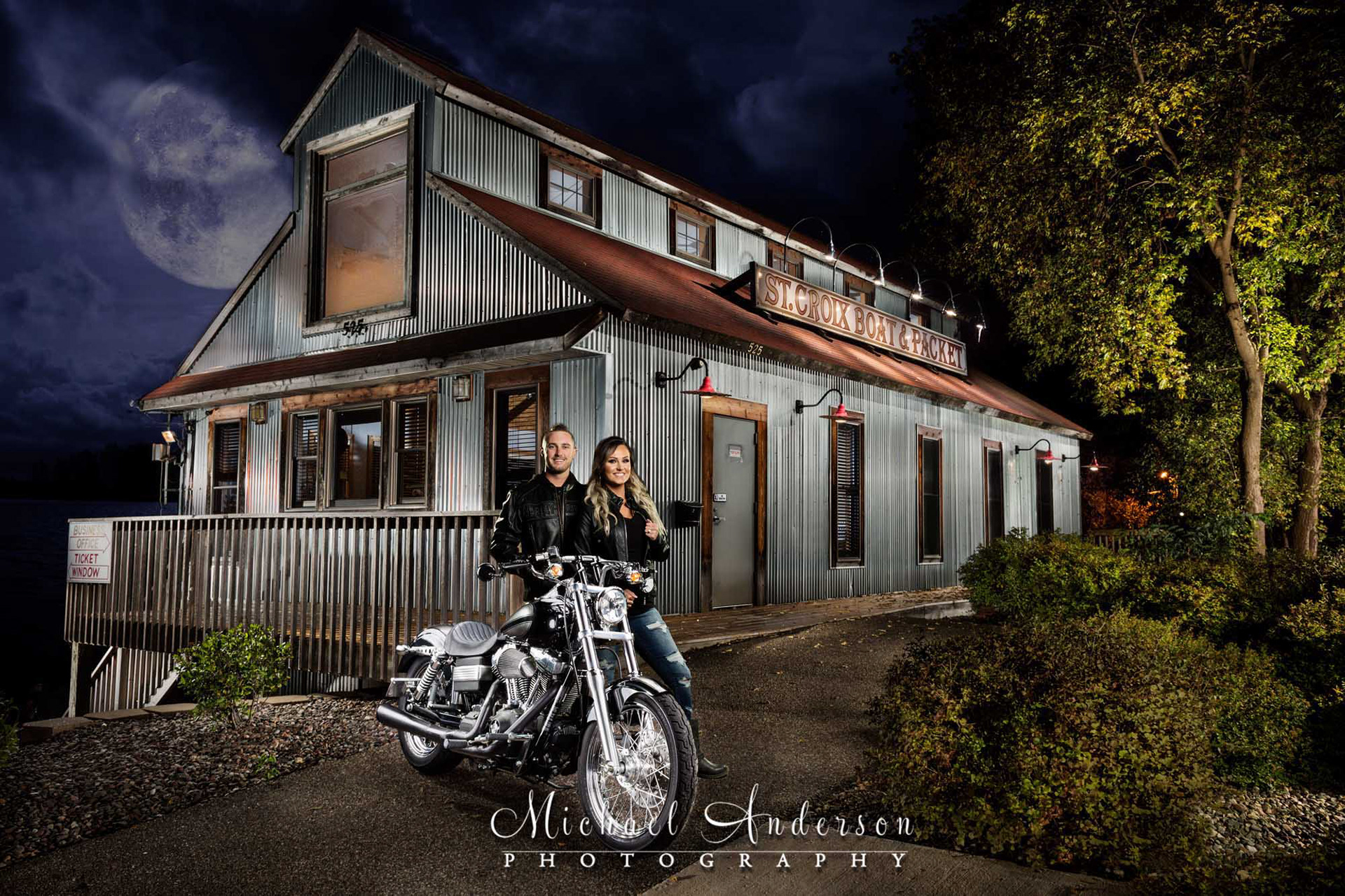 Light painted engagement photo of a cute couple and their Harley Davidson Motorcycle created at the St. Croix Boat & Packet building in Stillwater, MN.