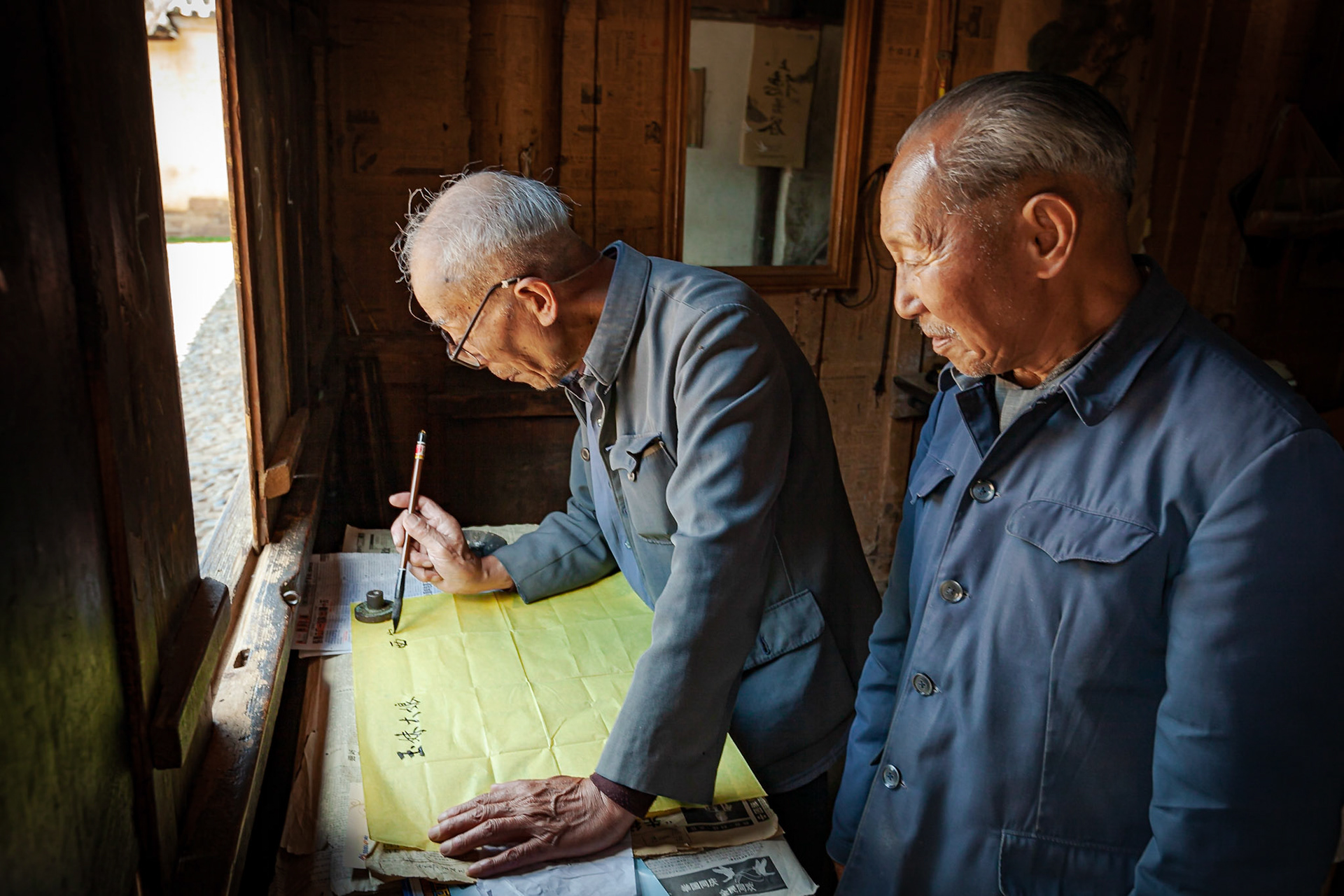 A Chinese Calligrapher making signs using traditional calligraphy in his shop in Shaxi, Yunnan Province, China.