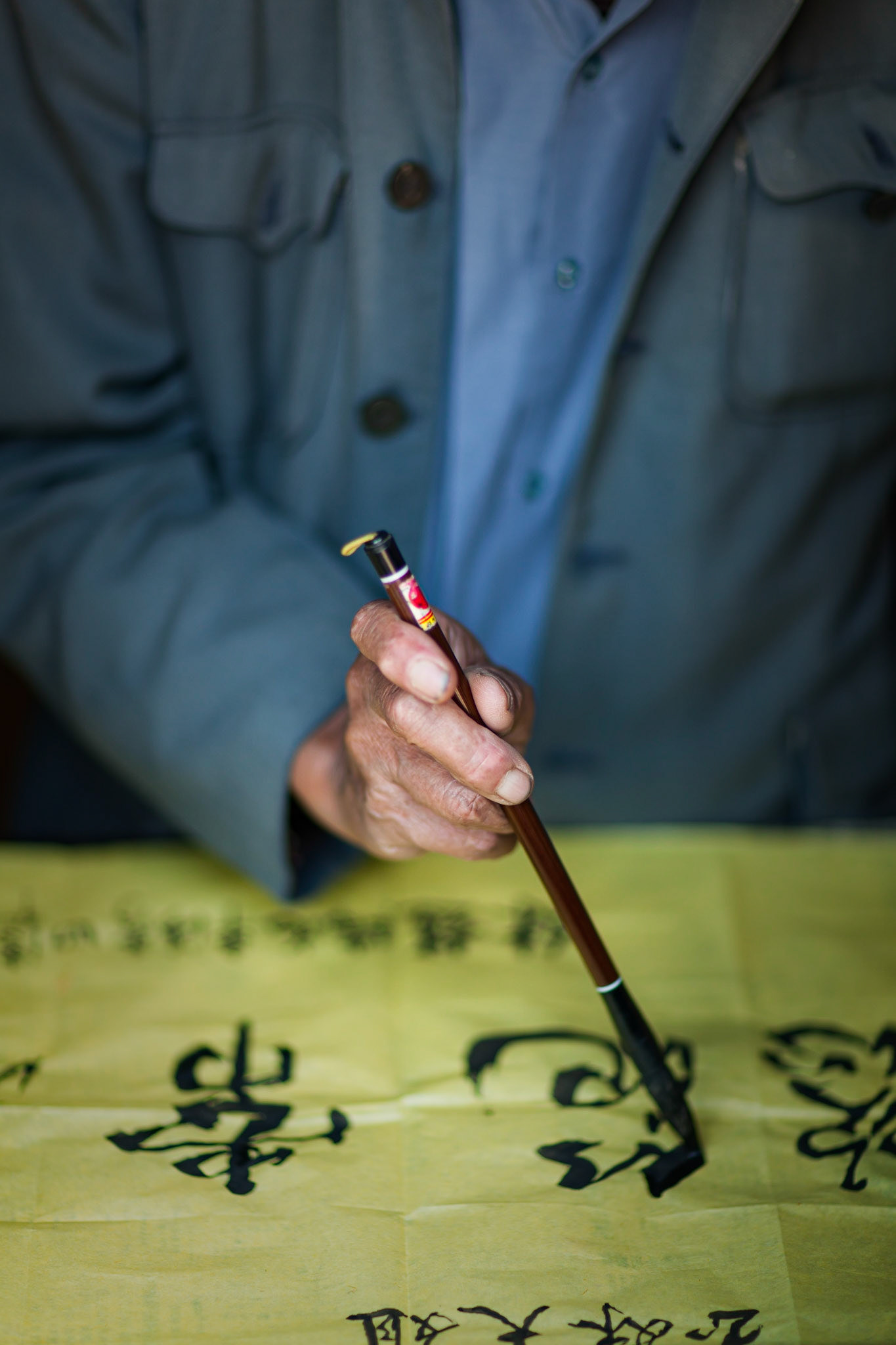 A Chinese Calligrapher making signs using traditional calligraphy in his shop in Shaxi, Yunnan Province, China.