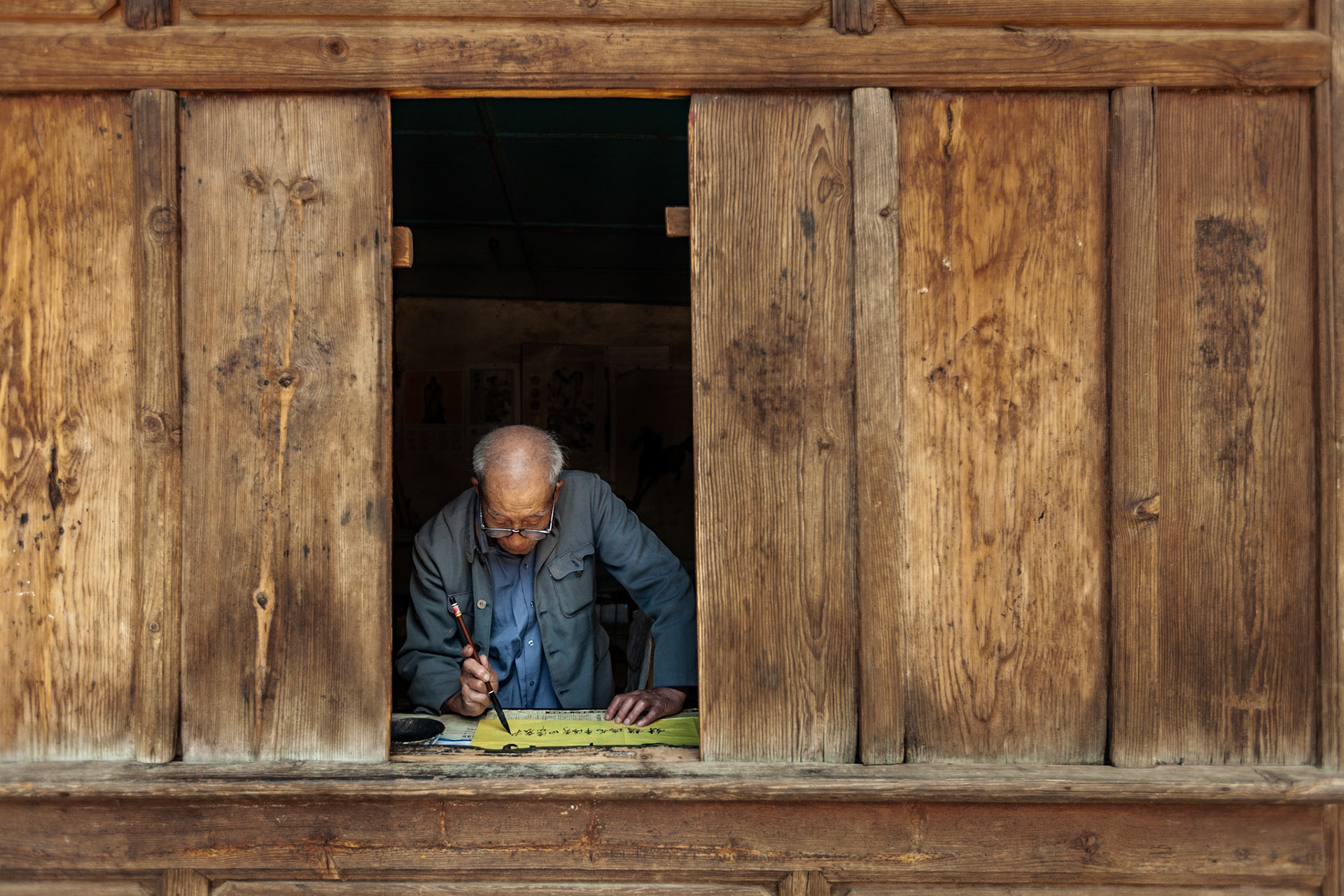 A Chinese Calligrapher making signs using traditional calligraphy in his shop in Shaxi, Yunnan Province, China.