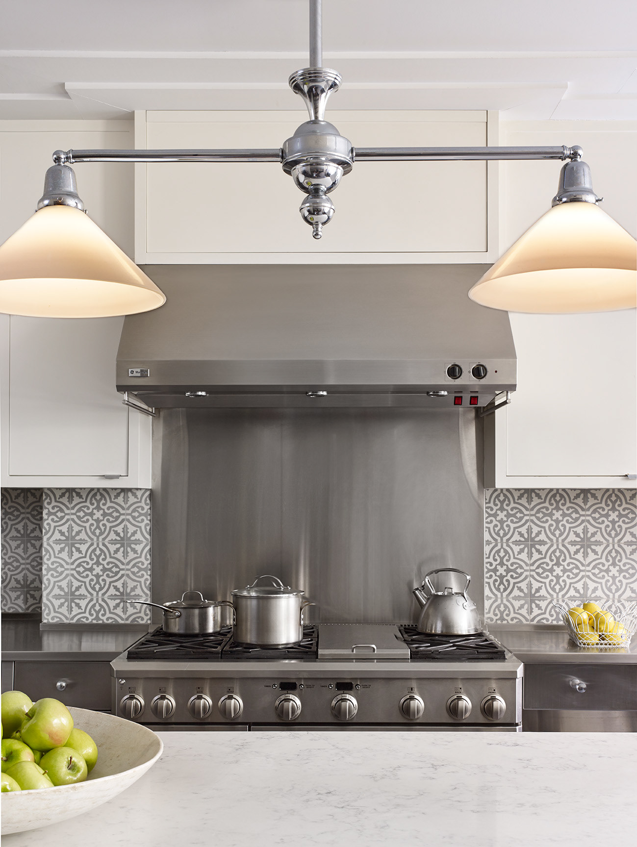 Kitchen with GE Monogram range and hood and billiard light over the kitchen island.