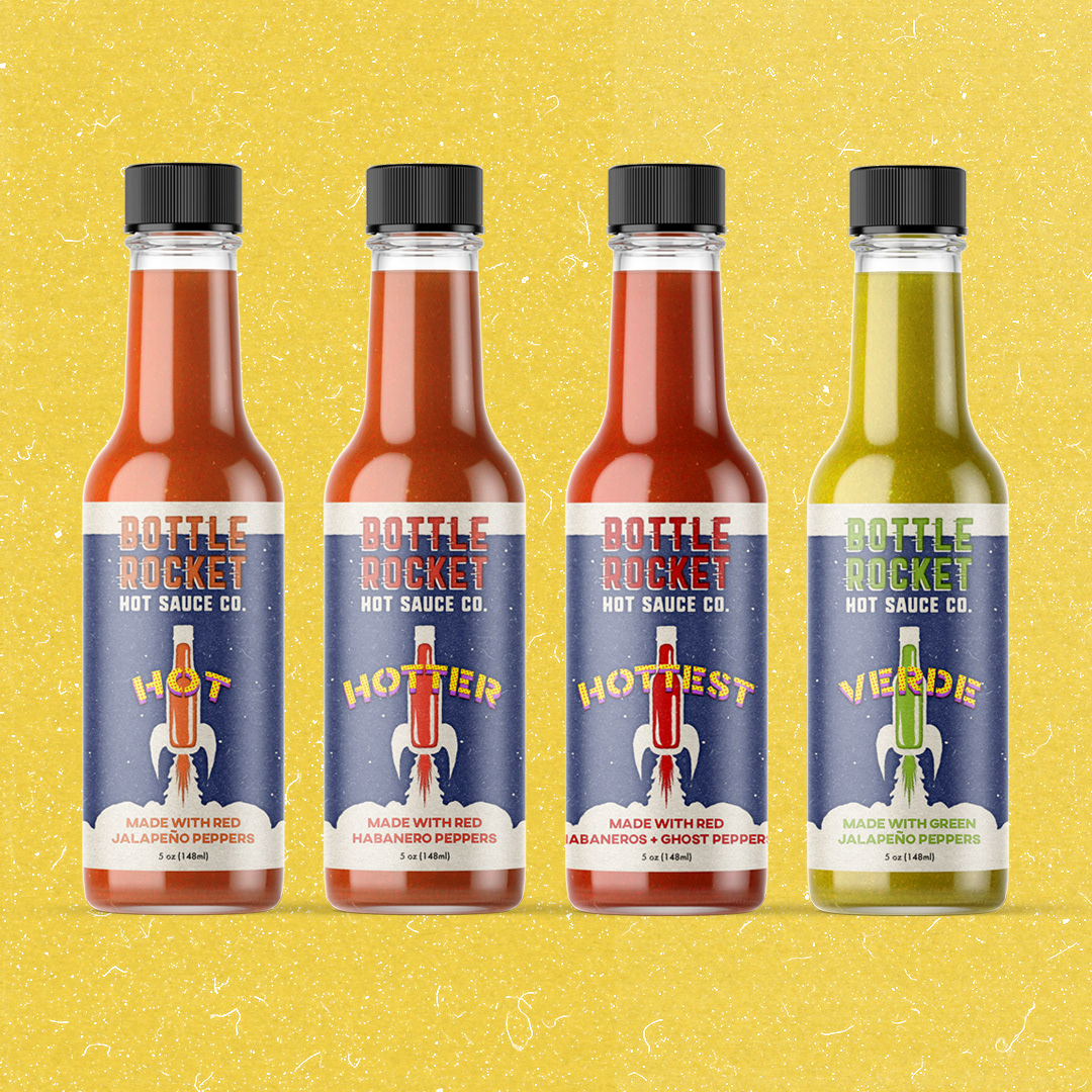 Four hot sauce bottles on a yellow background.