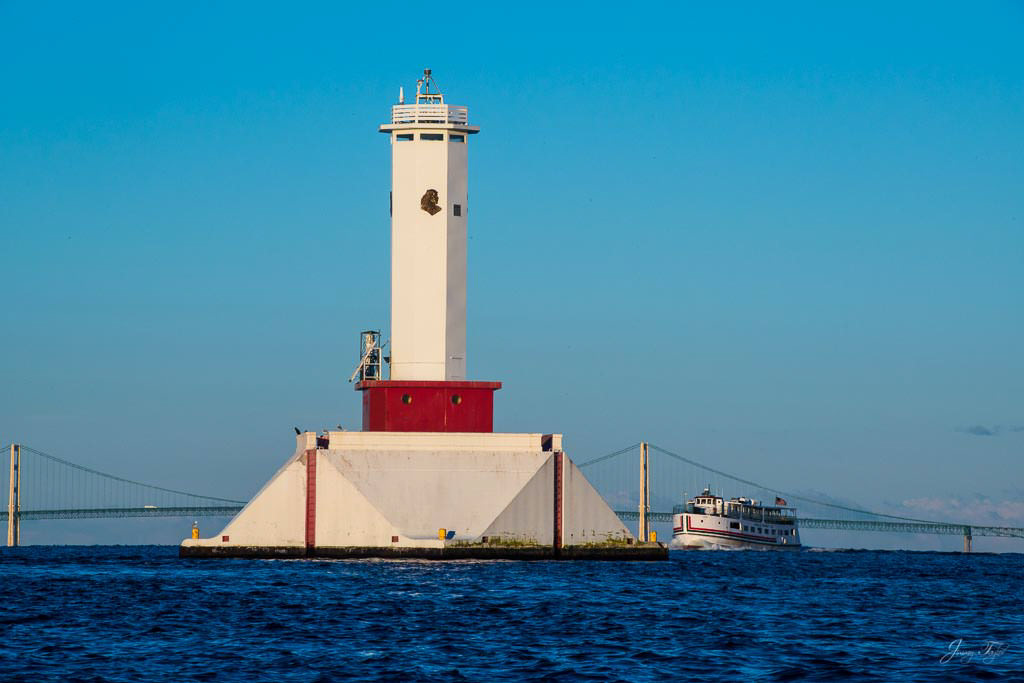 Mackinac Island sunrise with bridge, lighthouse and approaching ferry in the distance