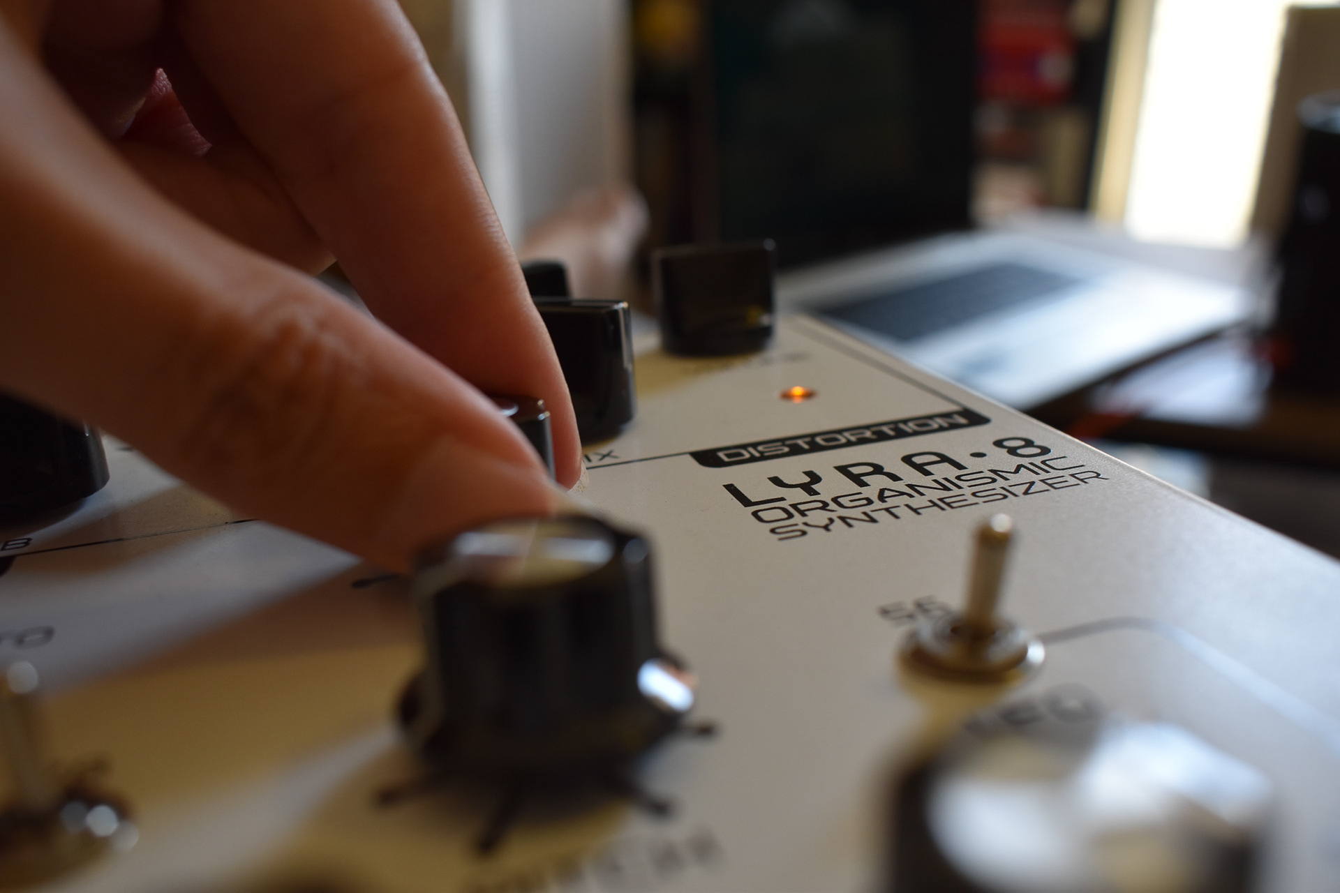 A close up of two fingers grabbing a button on a synthesizer