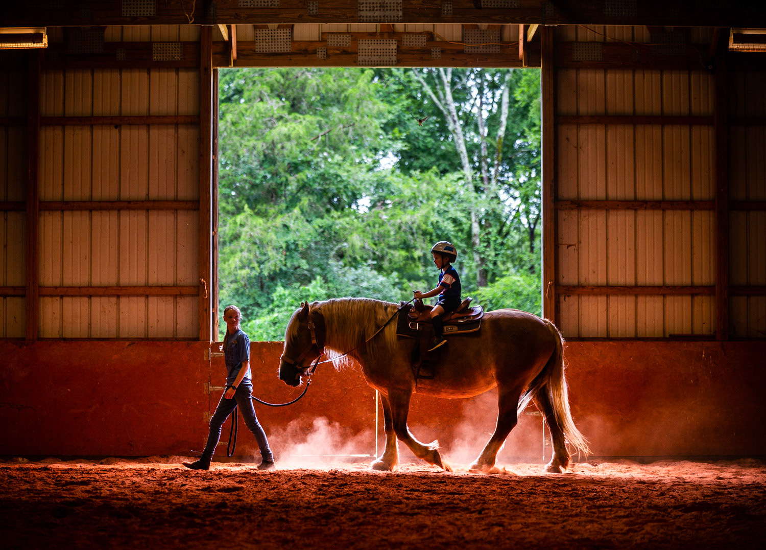 Jonah King, right, enjoys a horseback ride on 16-year-old Dolly, pulled by camp counselor Heidi Schrader on July 18 at Pine Ridge Day Camp in Somerville.